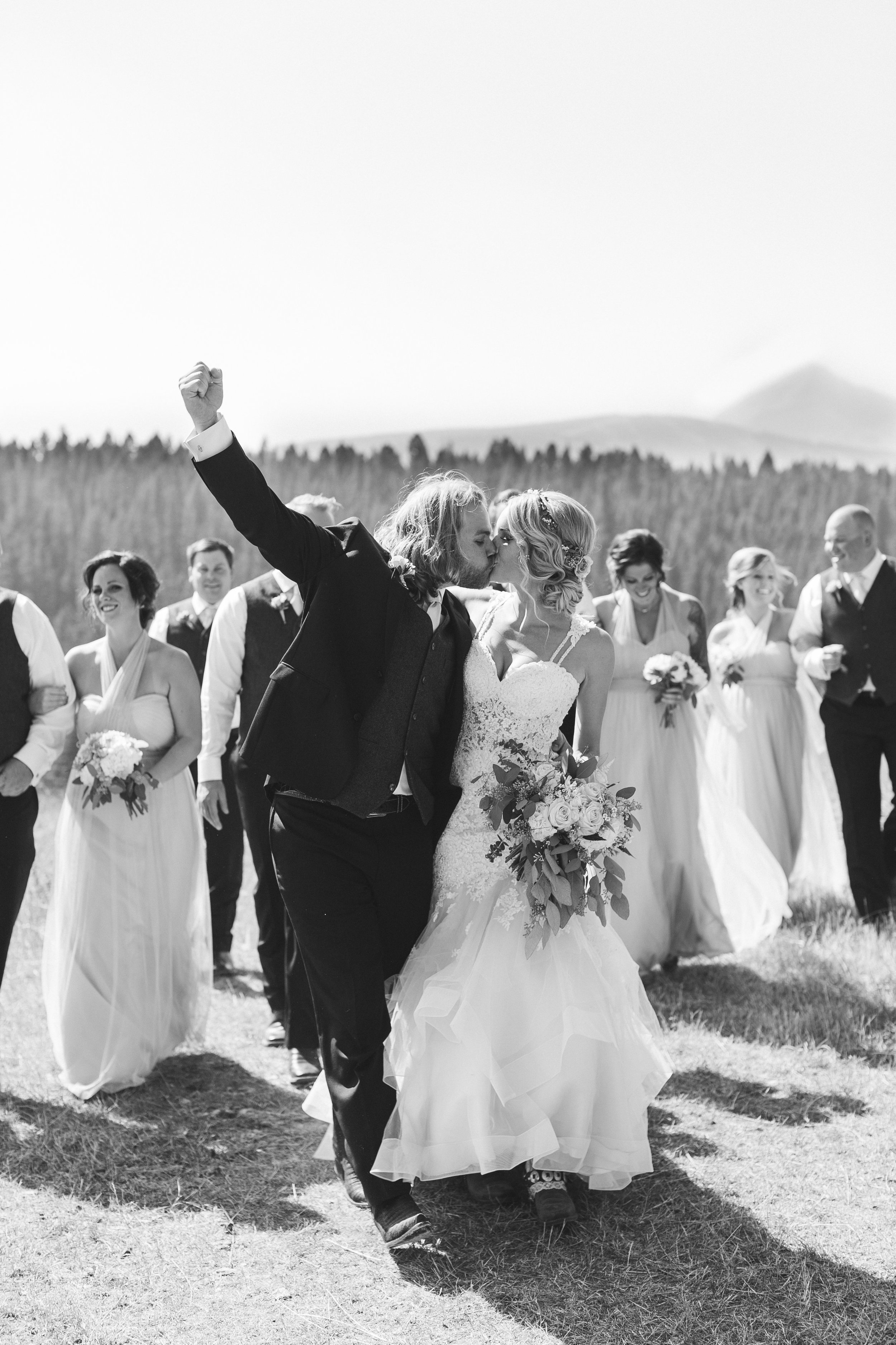 Montana bride and groom on mountain kissing and fist pumping Minnesota wedding photography Mallory Kiesow Photography