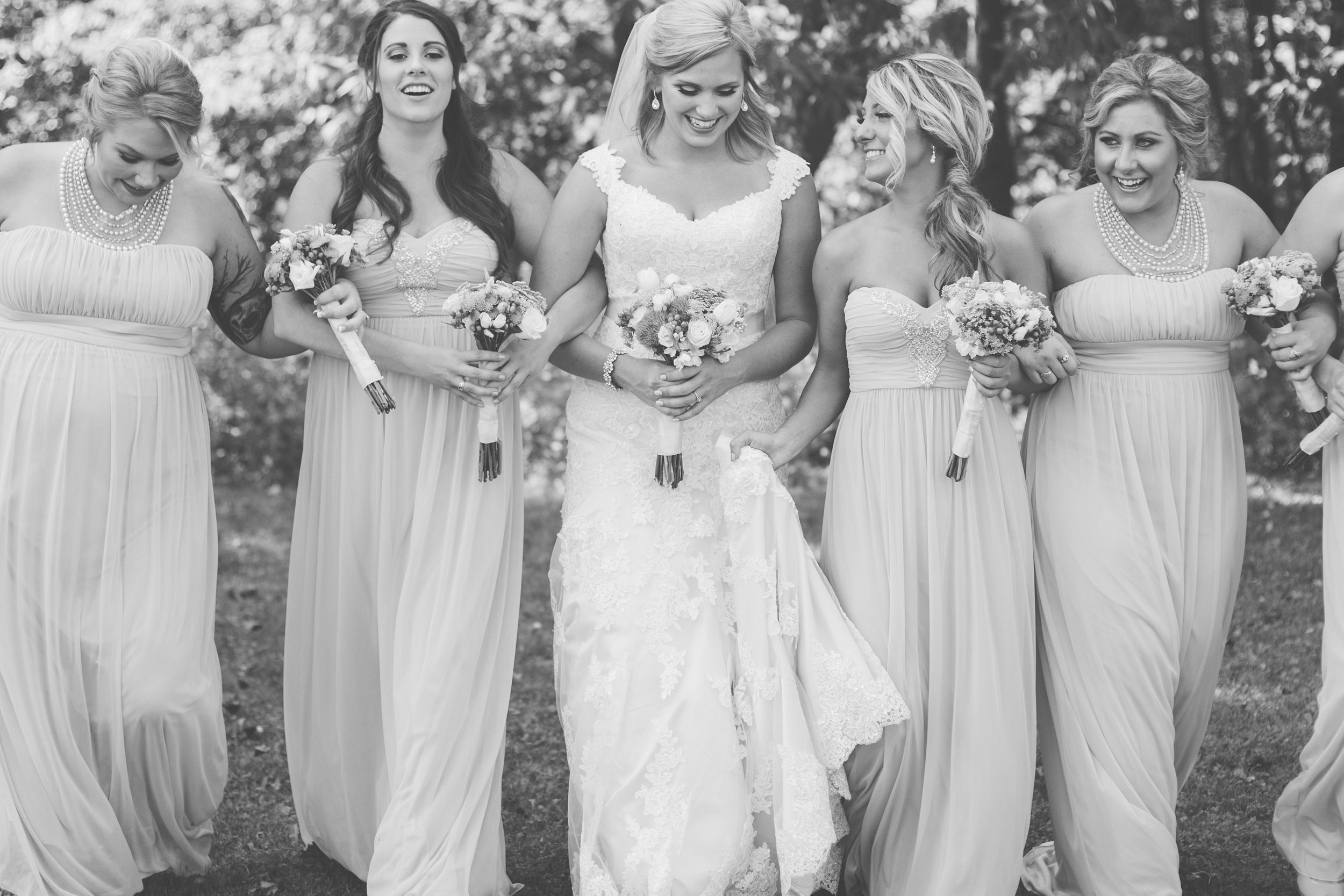 Bride and bridesmaids laughing and walking in Minnesota summer wedding black and white photo Minnesota wedding photography Mallory Kiesow Photography