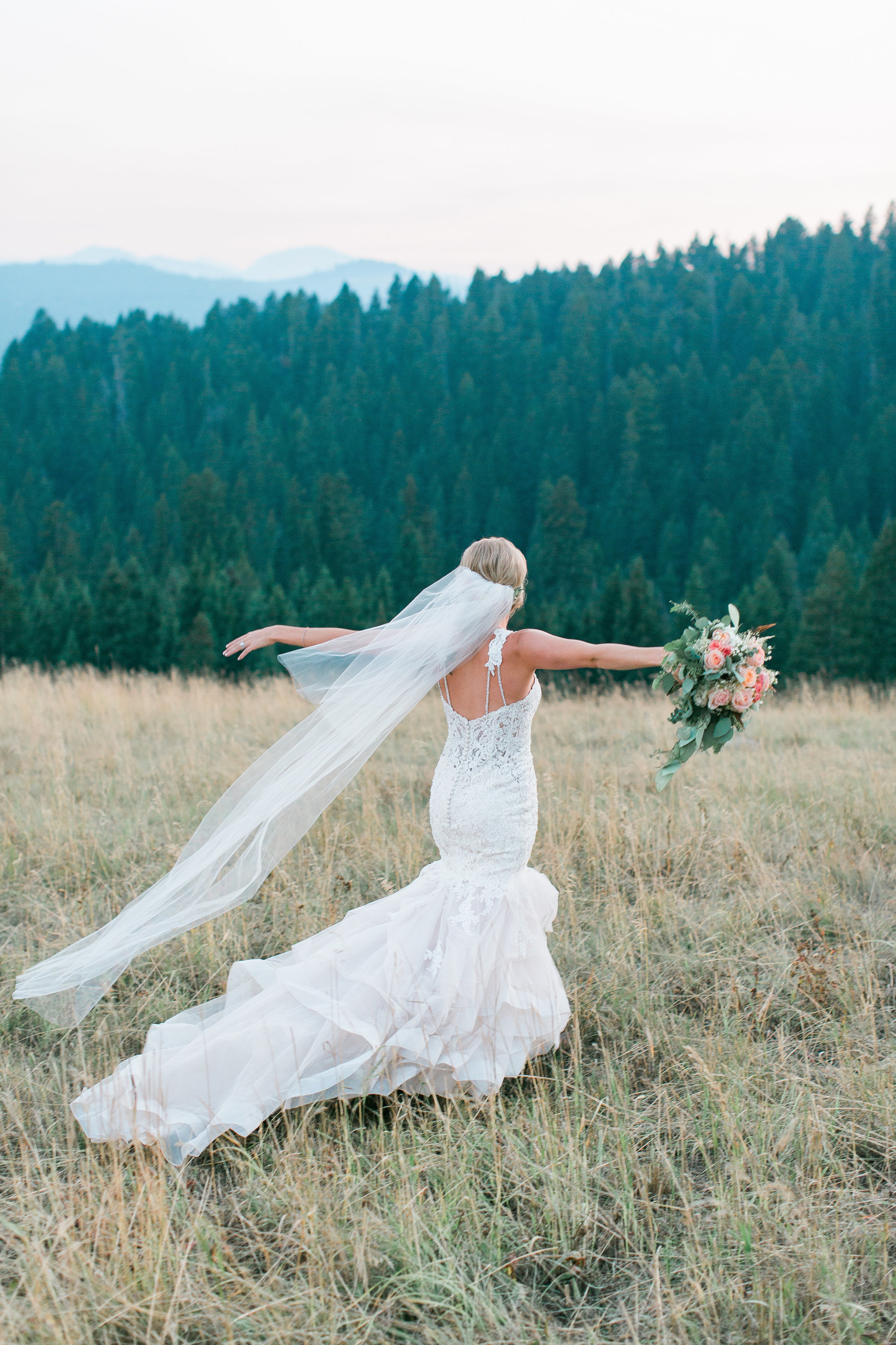Boho bride walking with arms out free spirit and mountains in background Big Sky Montana Lone Mountain Ranch wedding Minnesota wedding photography Mallory Kiesow Photography