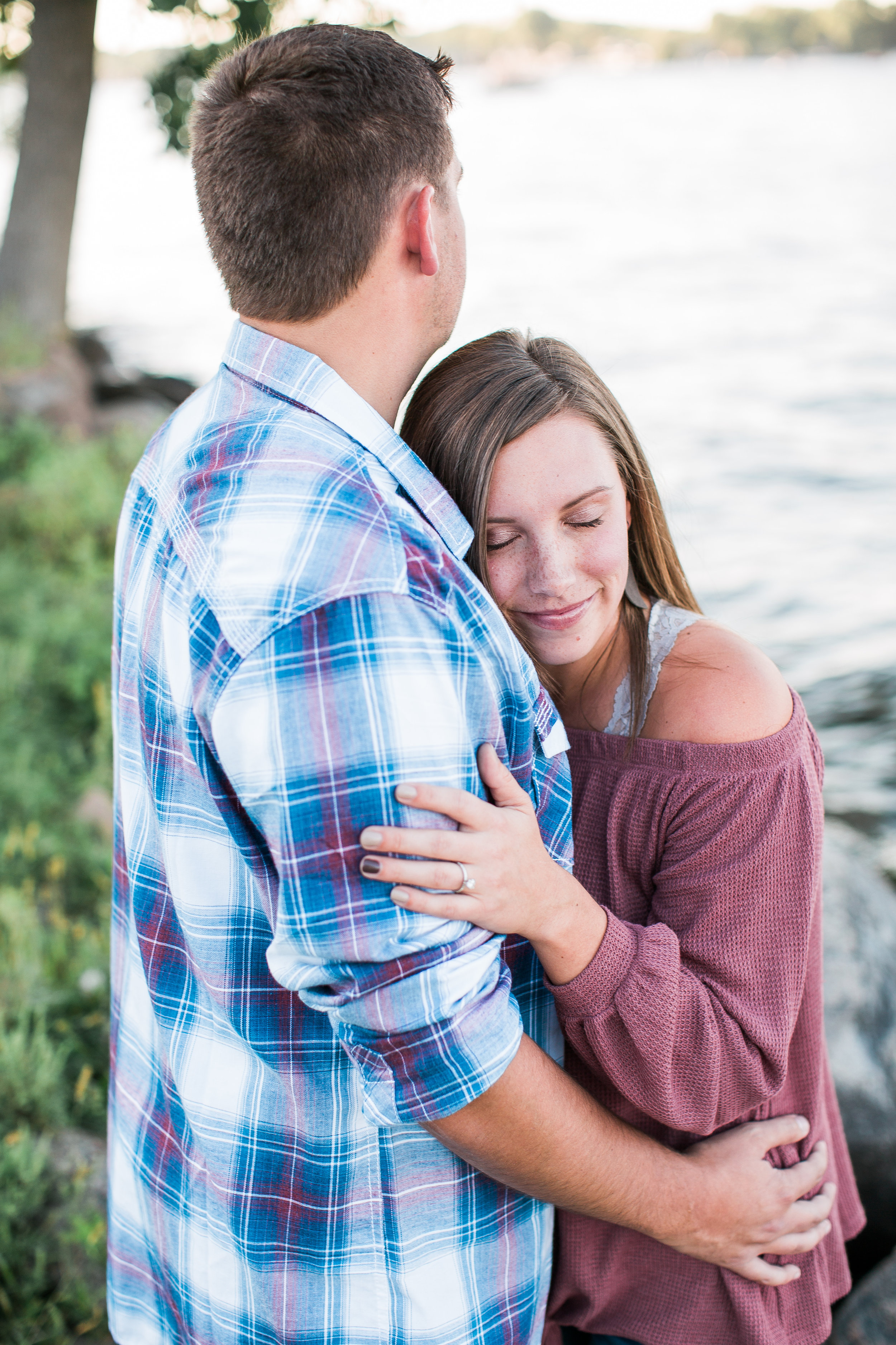 Engaged couple embracing in Excelsior Minnesota along Lake Minnetonka for engagement session Minnesota engagement photographer Mallory Kiesow Photography