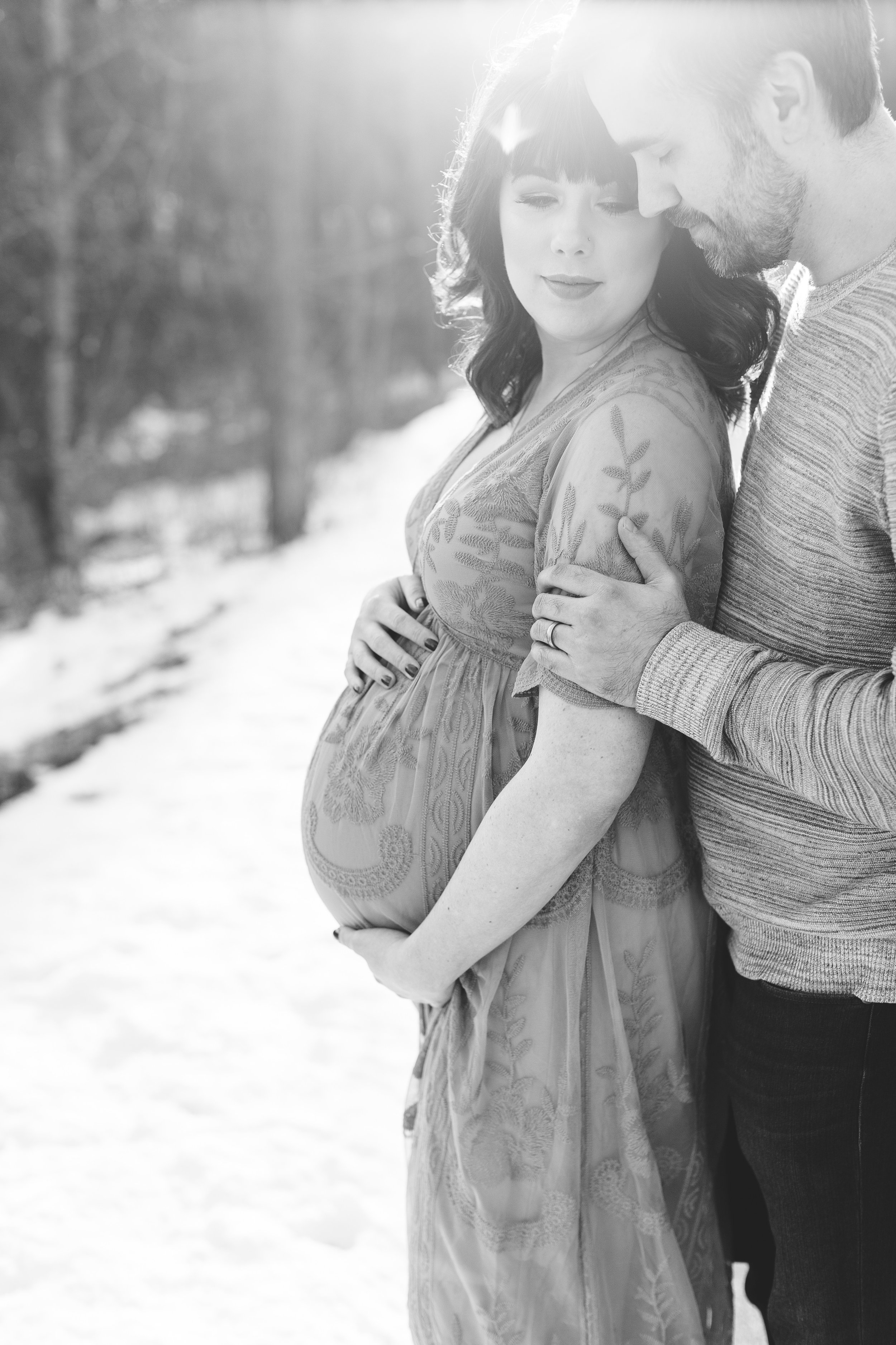 Pregnant mom and dad to be in black and white photo holding belly in winter maternity session Minnesota maternity photographer Mallory Kiesow Photography