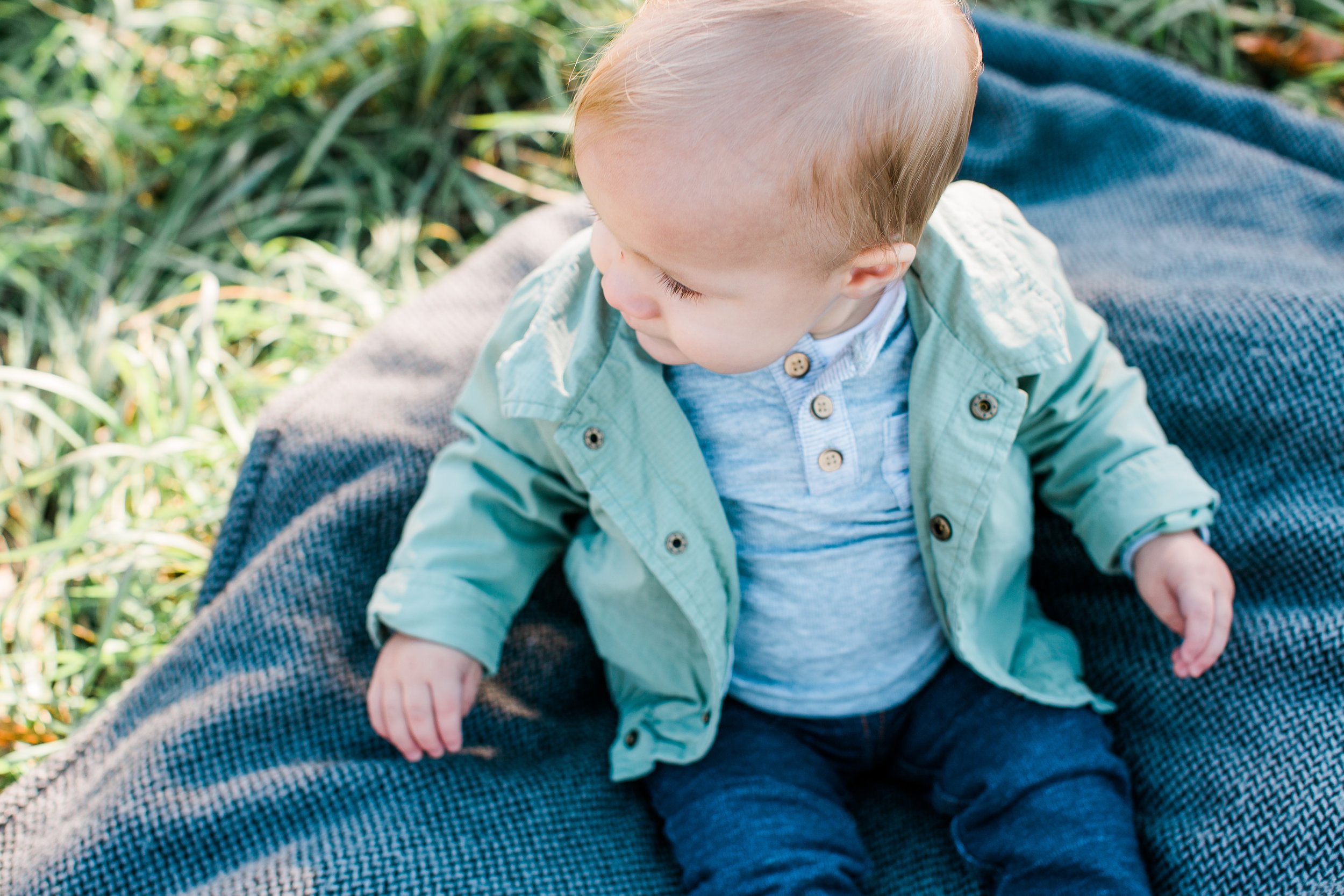 Blone baby boy portrait with green jacket jeans and long eyelashes Minnesota family photographer Mallory Kiesow Photography