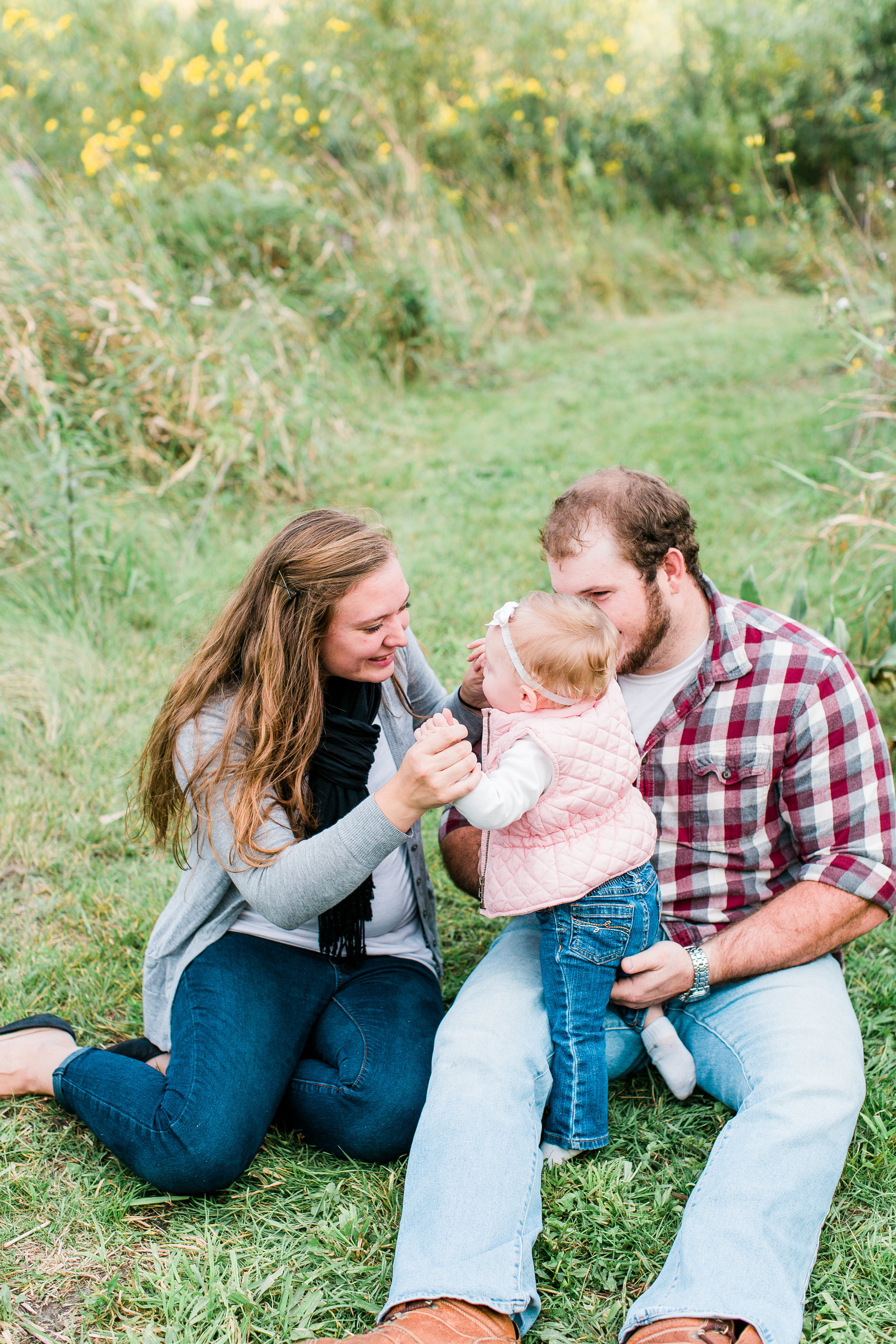 Mom, Dad, and baby sitting playing in the grass in Minnesota summer family session Minnesota family photographer Mallory Kiesow Photography