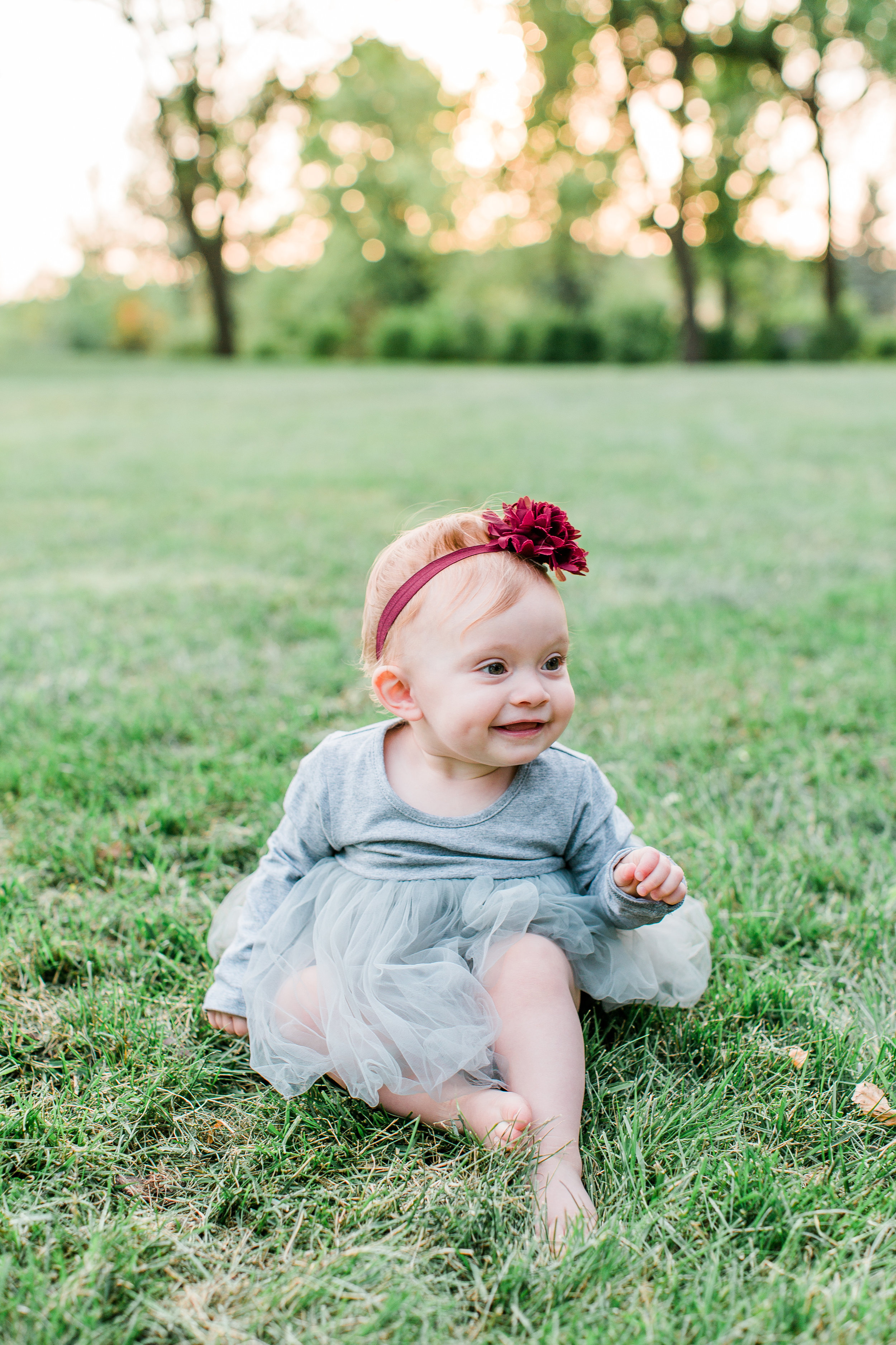 One year old girl in gray tutu dress and burgundy bow in the grass Minnesota family photographer Mallory Kiesow Photography