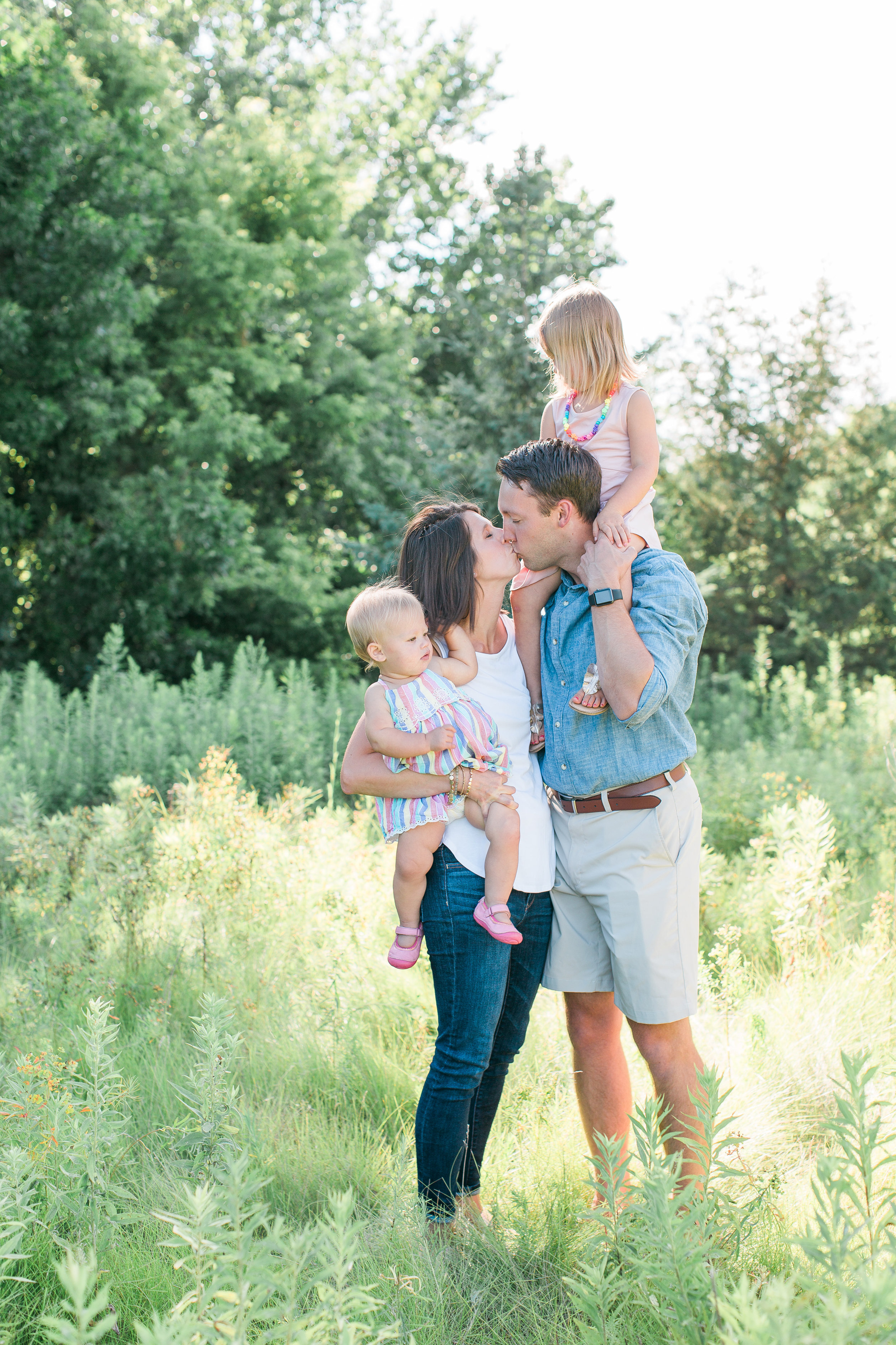 Family with husband, wife, toddler and baby in family portrait mom and dad kissing Minnesota family photographer Mallory Kiesow Photography