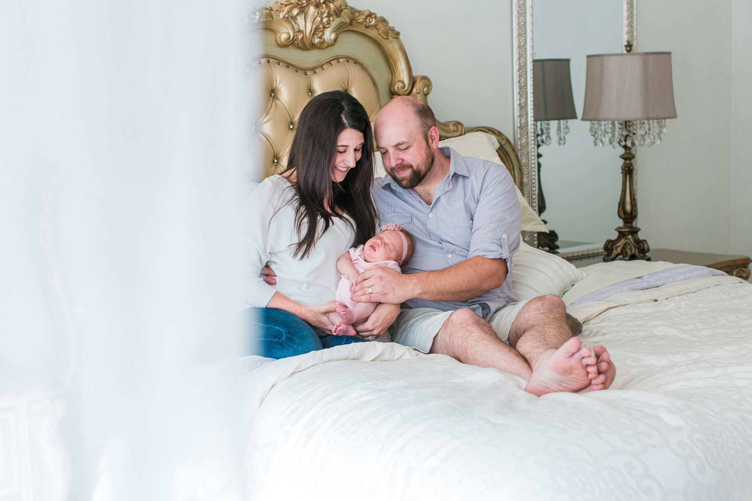 New parents with baby on bed in lifestyle in-home newborn session Minnesota newborn photographer Mallory Kiesow Photography