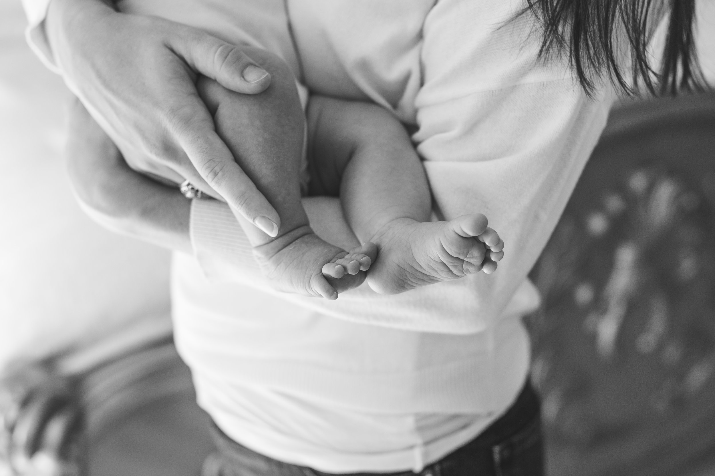 New mom with baby feet black and white photo in-home newborn session Minnesota newborn photographer Mallory Kiesow Photography