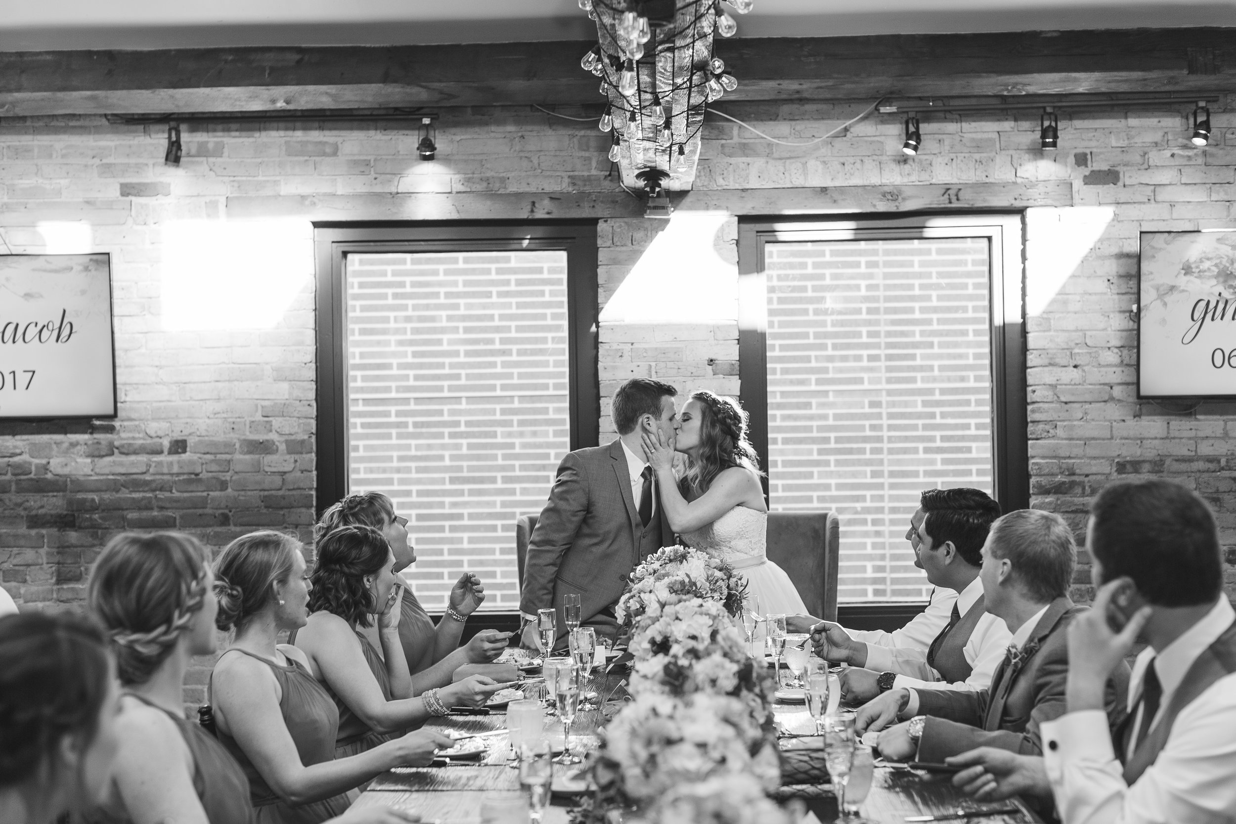 Bride and groom kissing at head table during reception in black and white at Minneapolis Event Centers wedding Minnesota wedding photography Mallory Kiesow Photography