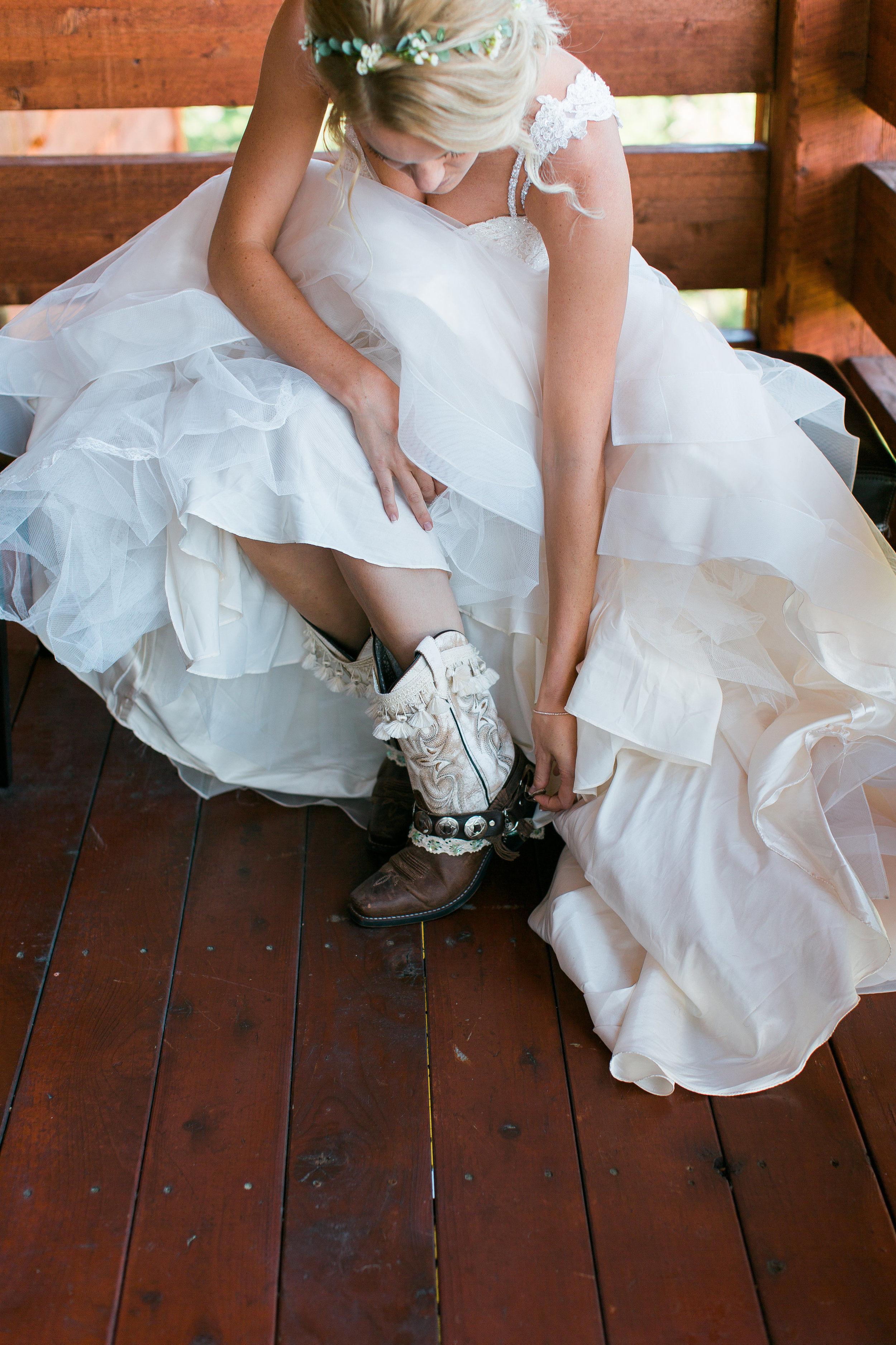 Boho bride putting on cowboy boots Montana Lone Mountain Ranch wedding Minnesota wedding photography Mallory Kiesow Photography