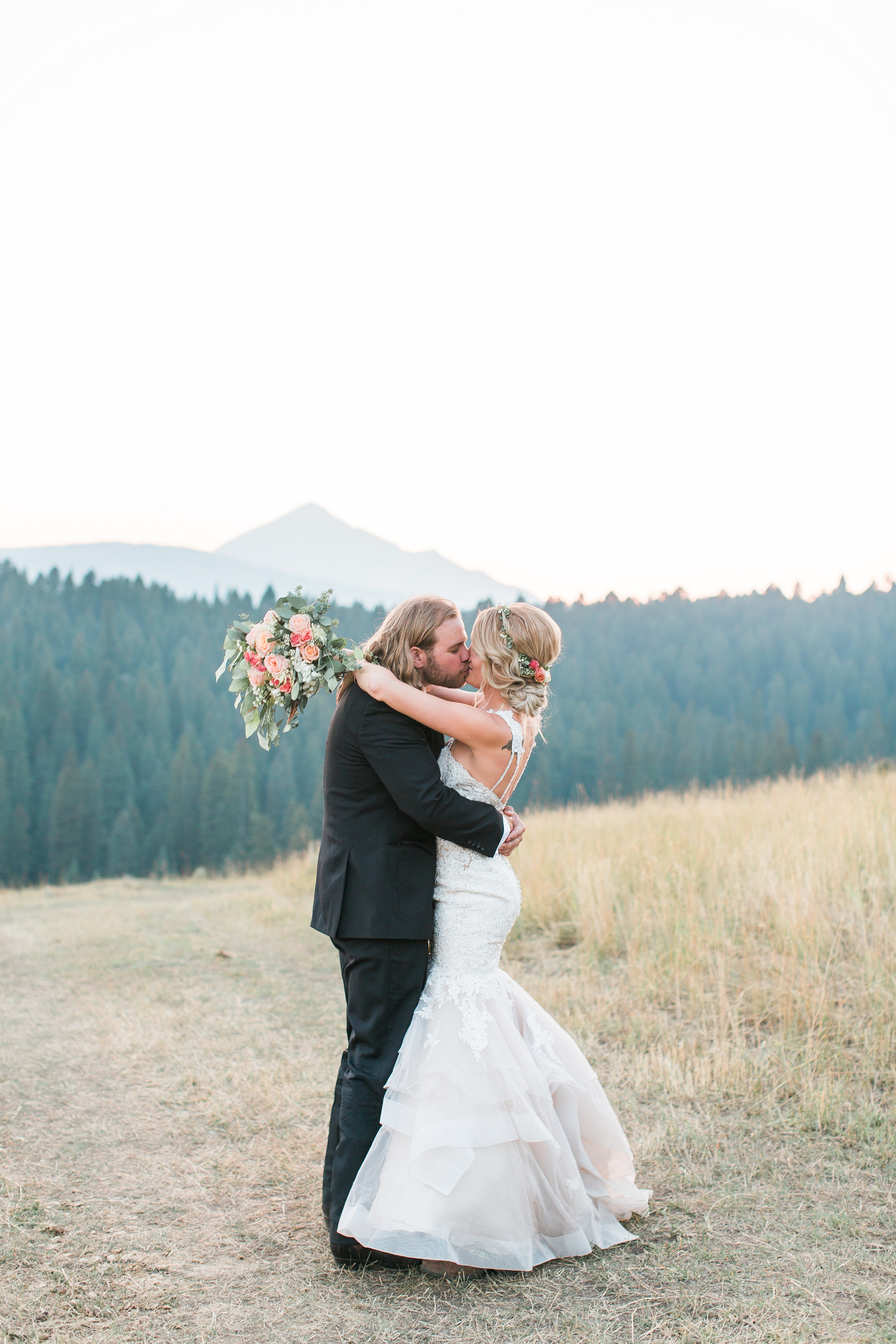 Boho bride and groom kissing with mountains in the background in Big Sky Montana Lone Mountain Ranch wedding Minnesota wedding photography Mallory Kiesow Photography