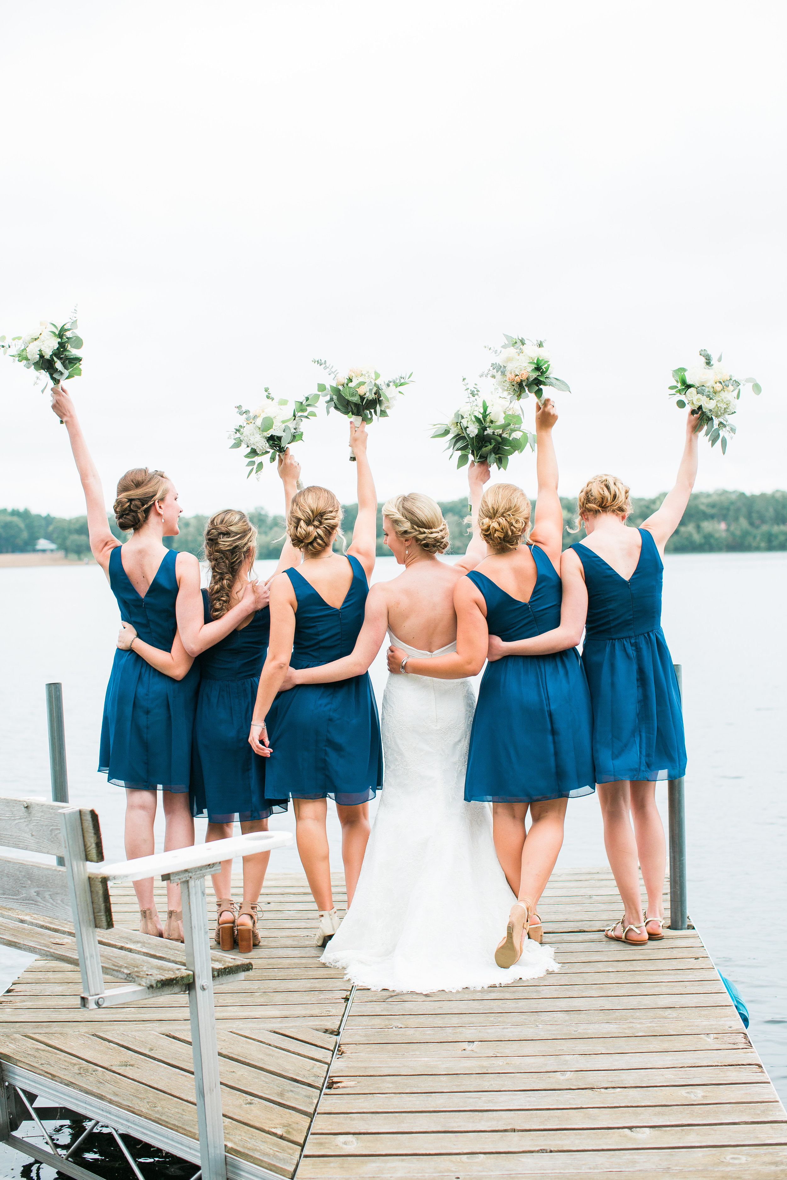 Nisswa Minnesota lakeside wedding bridesmaids celebrating with bouquets on dock Minnesota wedding photography Mallory Kiesow Photography