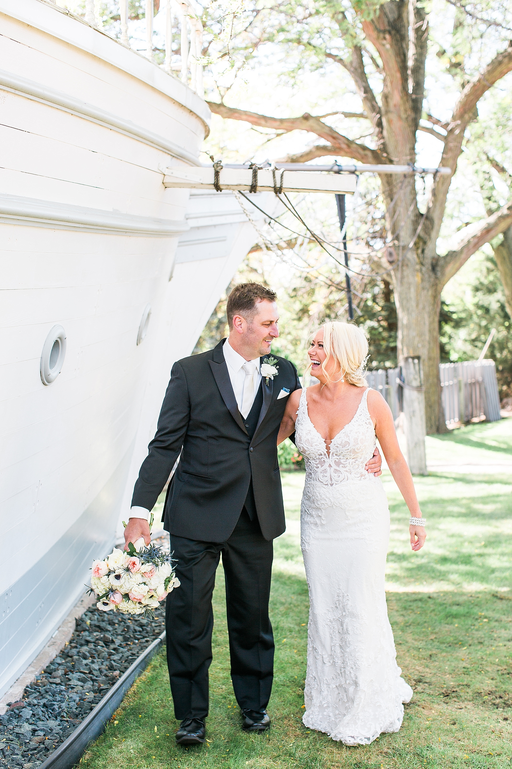 Bride and groom walking next to ship on wedding day at the Chart House Summer Wedding Lakeville Minnesota Minneapolis Wedding Photographer Mallory Kiesow