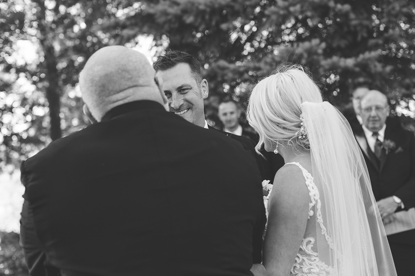 Outdoor wedding ceremony groom reaction to father giving away bride at the Chart House Summer Wedding Lakeville Minnesota Minneapolis Wedding Photographer Mallory Kiesow