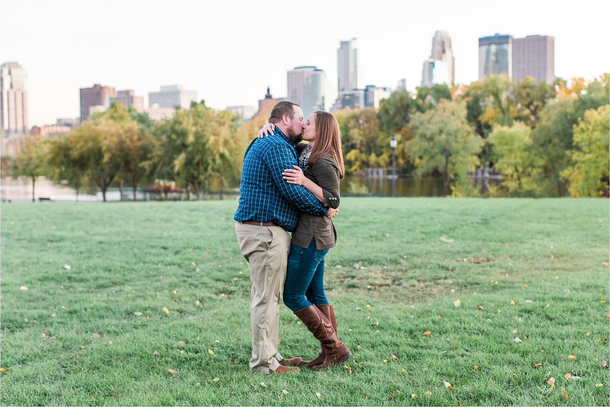 Engaged couple embracing with Minneapolis city skyline in the background at Boom Island Park in Minneapolis Mallory Kiesow Photography