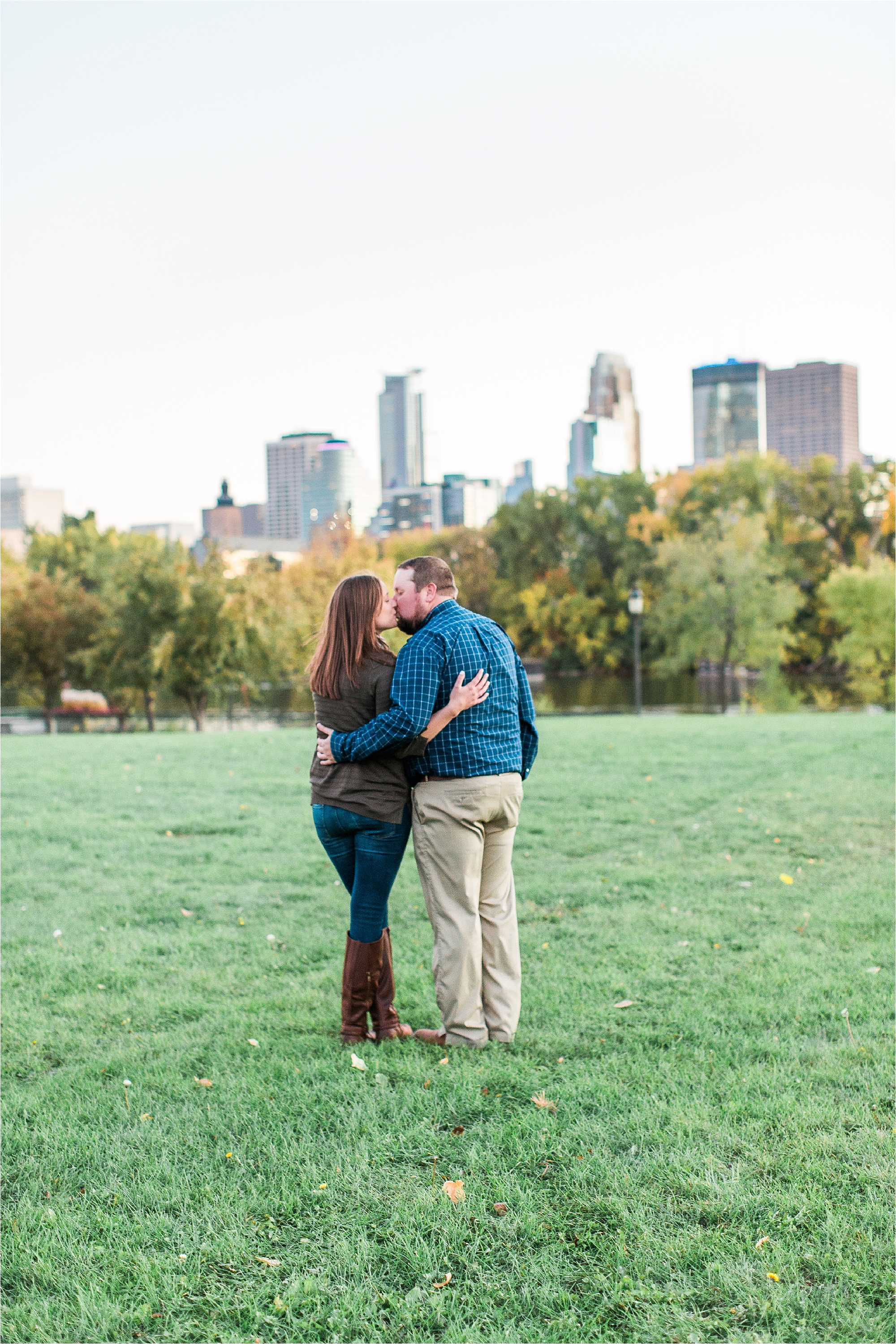 Engaged couple embracing and taking in view with Minneapolis city skyline in the background at Boom Island Park in Minneapolis Mallory Kiesow Photography