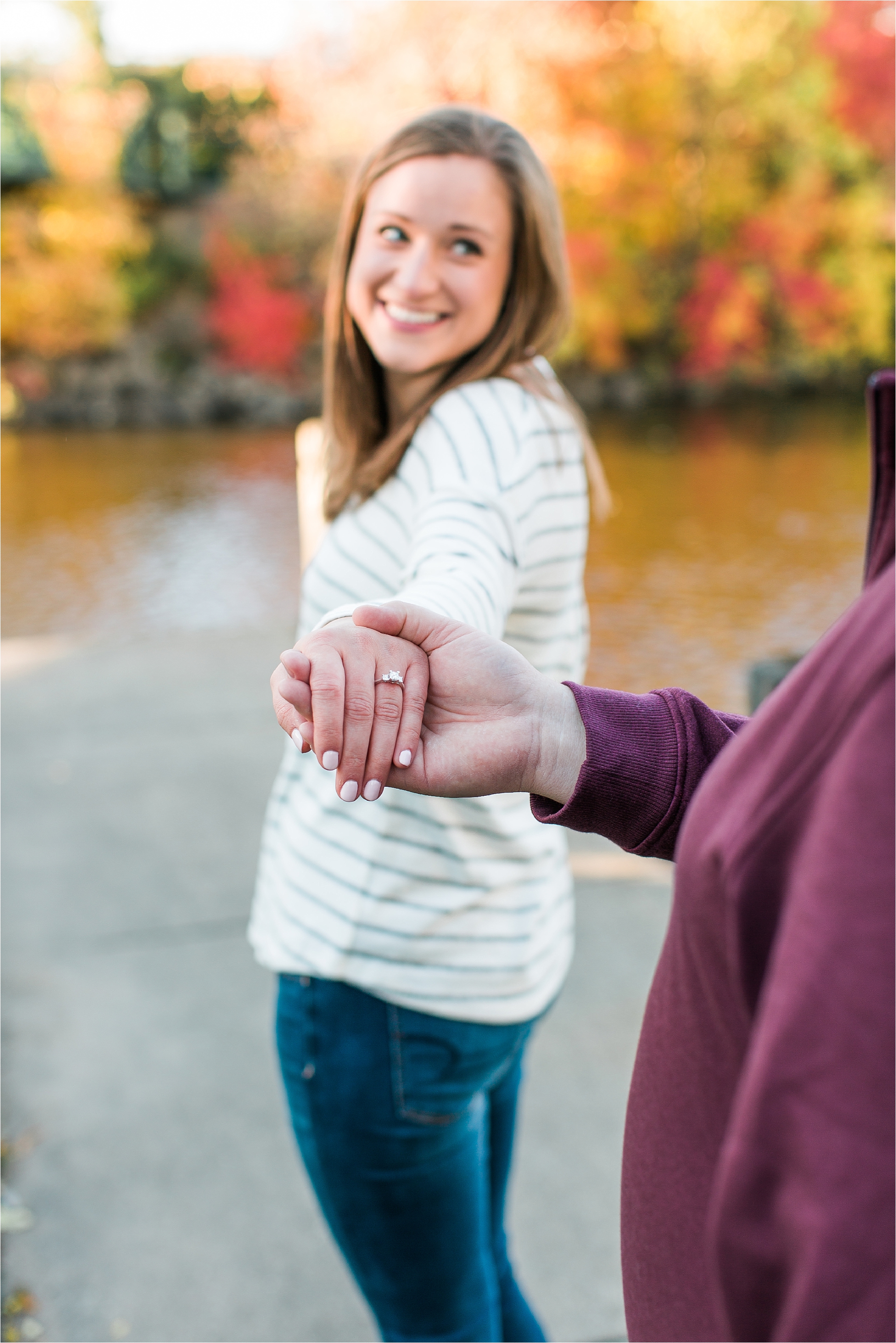Engaged couple bride to be walking showing engagement ring in Minneapolis fall engagement session at Boom Island Park in Minneapolis