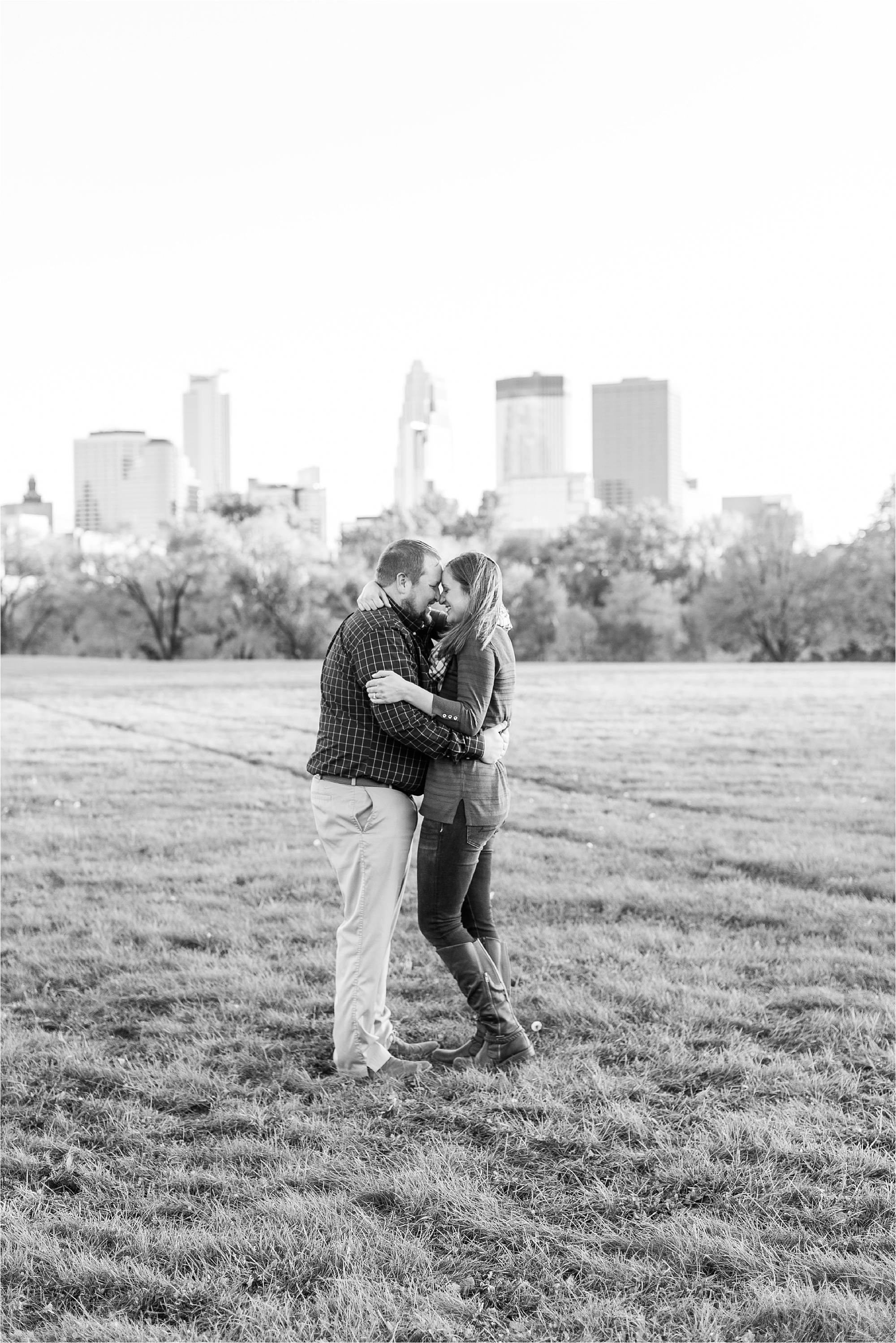 Engaged couple black and white photograph in front of Minneapolis skyline view at Minneapolis Fall engagement session at Boom Island Park in Minneapolis photographed by Mallory Kiesow