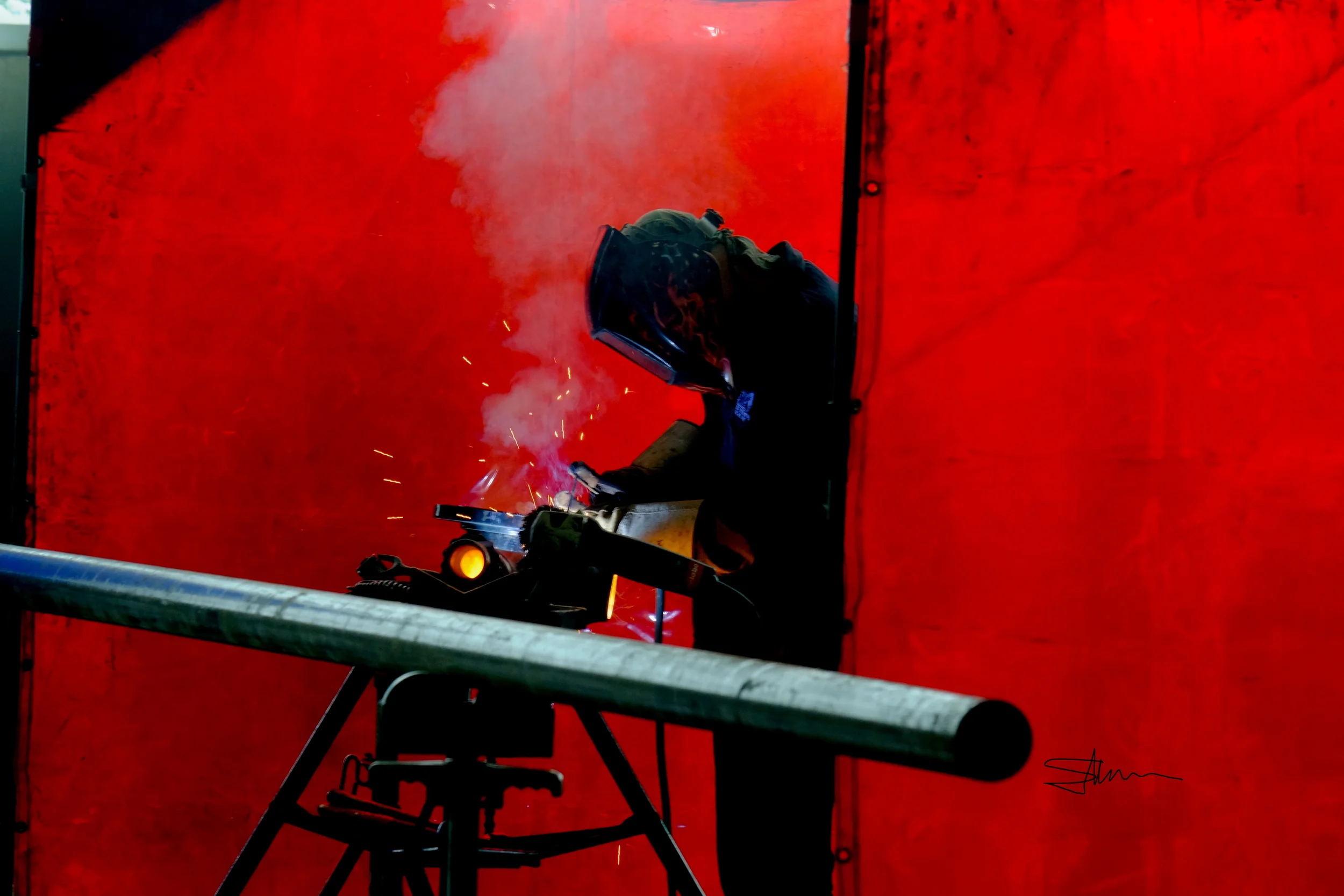 PressSide: Welder working on pipes for a new press