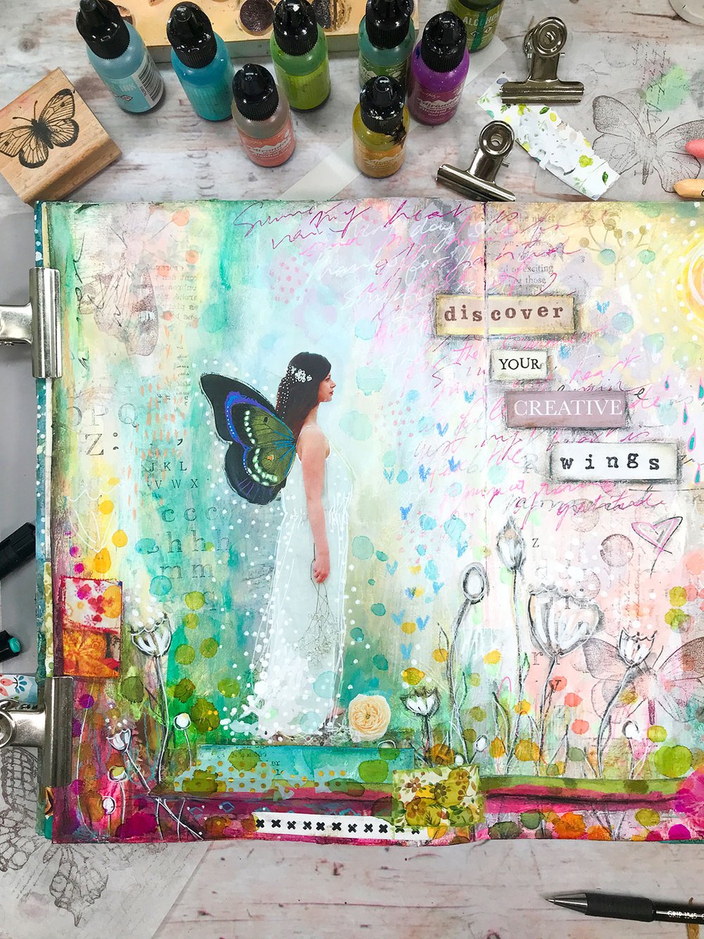 colorful mixed media art journal page with fairy and art supplies