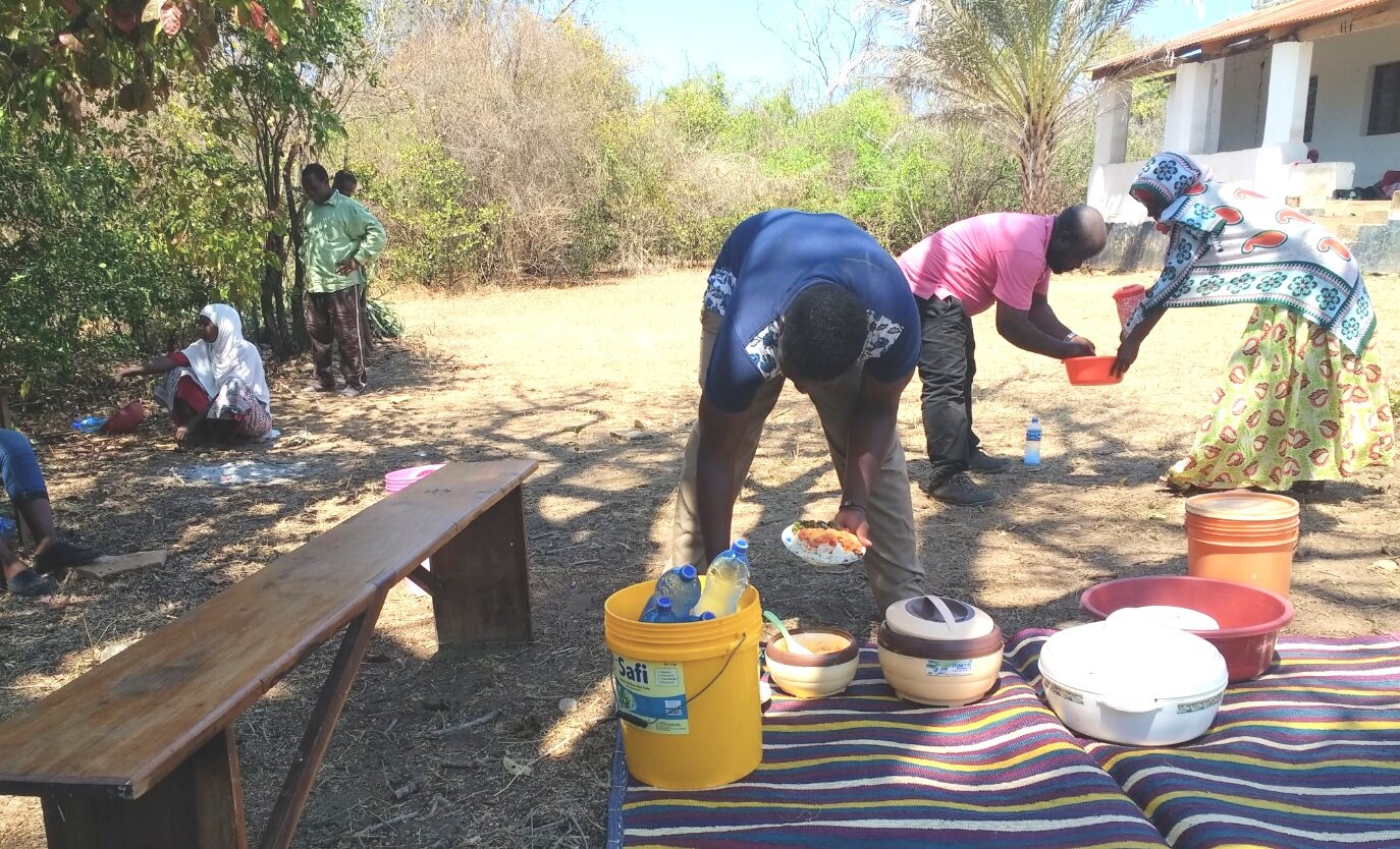 People serving meal of pickled mango with roasted fish made by SPI's kilwa womens group.png