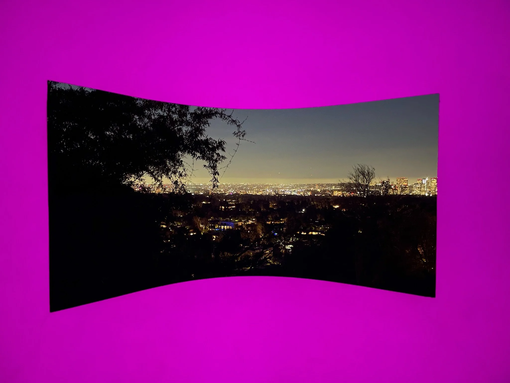 Detail of curved window in James Turrell Skyspace 'Above Horizon' at Sheats-Goldstein Residence, pink LED-lit interior framing glowing Los Angeles city lights beyond – preserved by Conner & Perry Architects