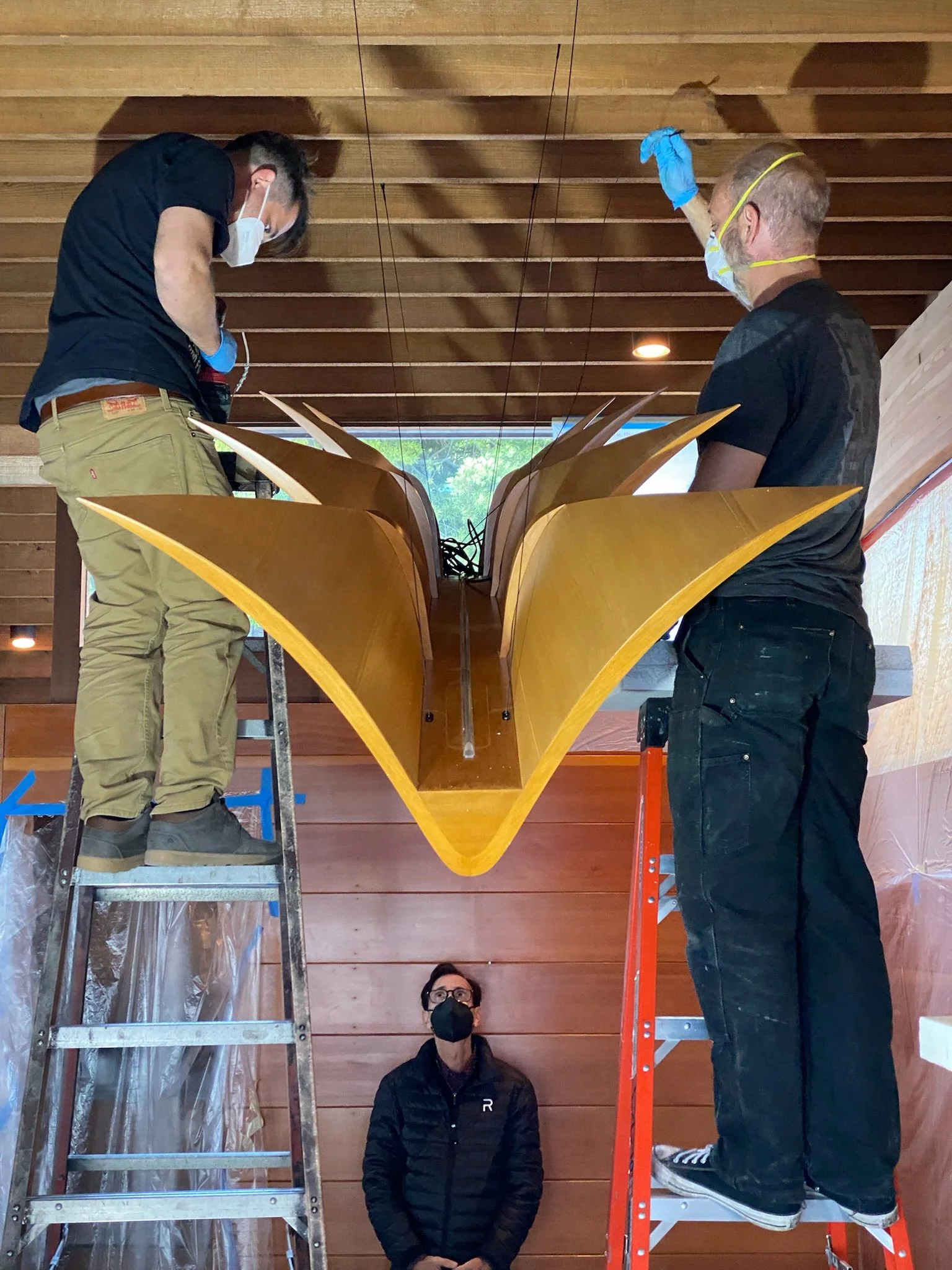 Installing and suspending the Dragon wood chandelier from the exposed glulam timber ceiling at Lautner's Castle.