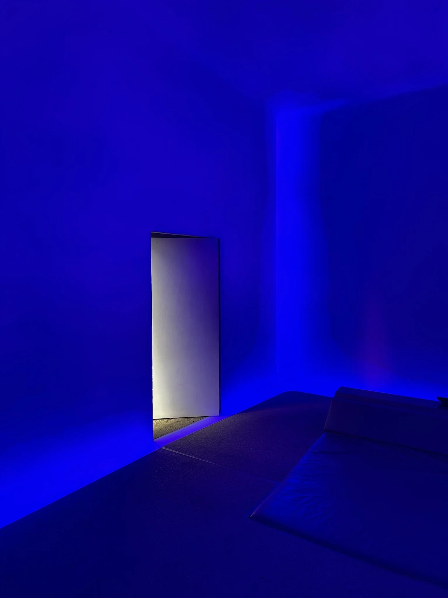 Interior of James Turrell Skyspace 'Above Horizon' at Sheats-Goldstein Residence, illuminated by intense blue LED light with daylight through open vault-style door – preserved by Conner & Perry Architects, Los Angeles