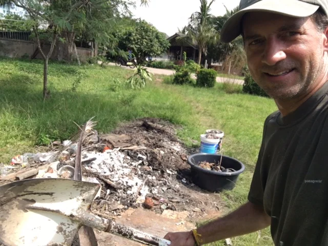 Digging up trash, loading it into buckets, and driving it by 3-wheeled motorbike to the other end of the property.