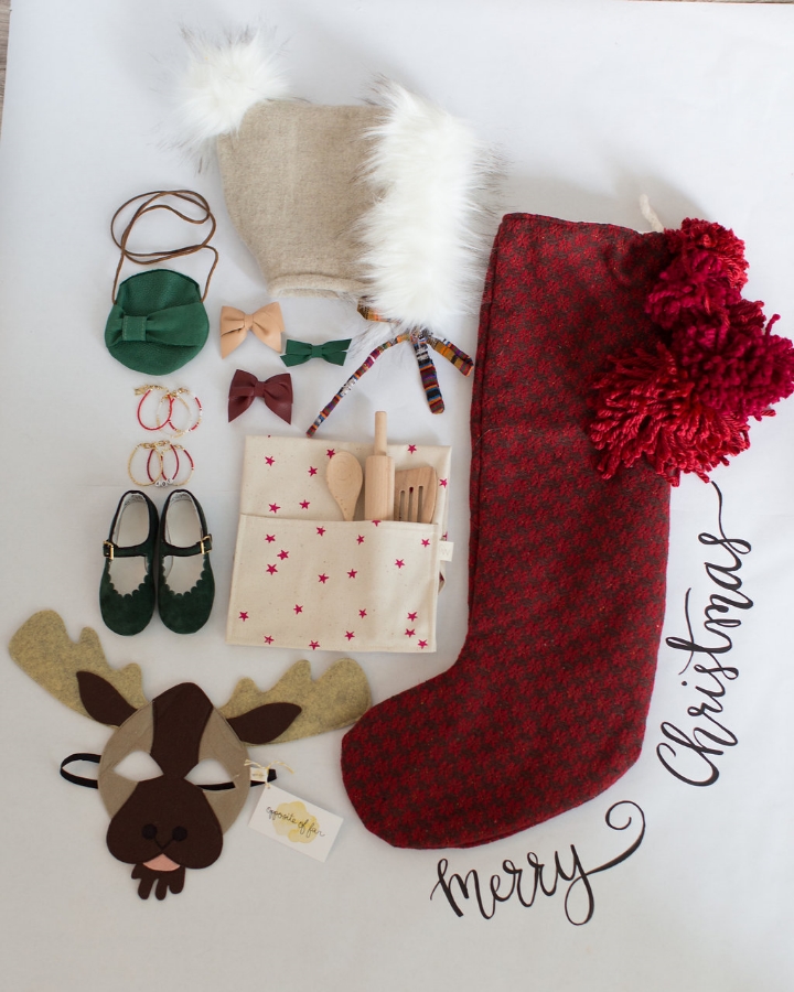 Styling by Mari Spiker, moose mask by Opposite of Far, stocking by Tinsel, children apron with wooden utensils by Odette Wiliams, purse by Raine and Skye, fur hat by Chapel and Rose, bracelets by Braided Mermaid, leather hair bows by Pitchoun Designs, and green mary janes by Zimmerman Shoes.