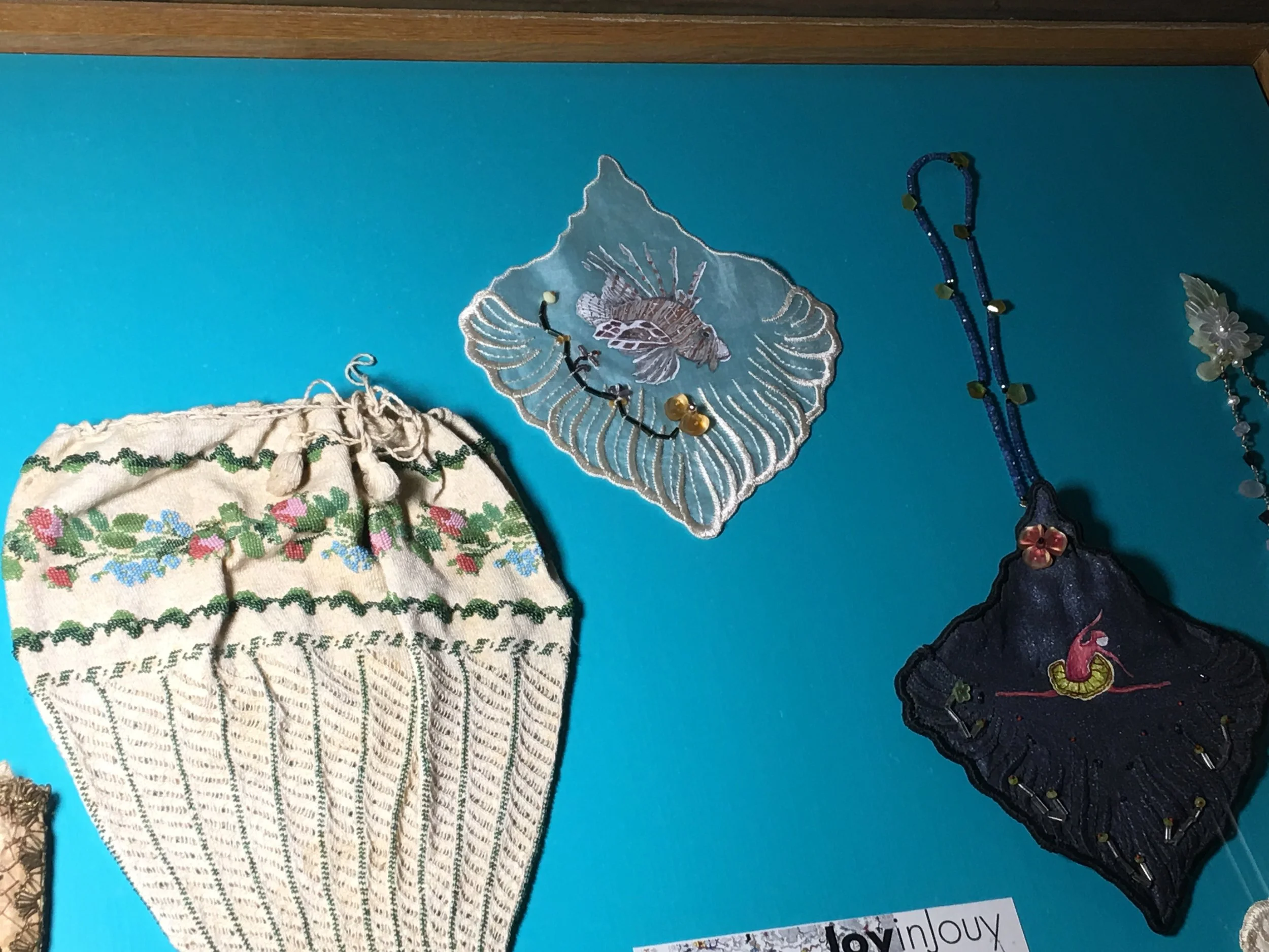 This photo shows one individual leaf from a vintage organza dress that I took apart. I hand paint and bead each leaf and then make a tiny little evening bag. The strap on the midnight blue bag is made of 14K gold and sapphires and us removable to wear as a necklace. These are shown in a case next to a vintage bag that is part of the permanent exhibit at La Musee de la Toile de Jouy.