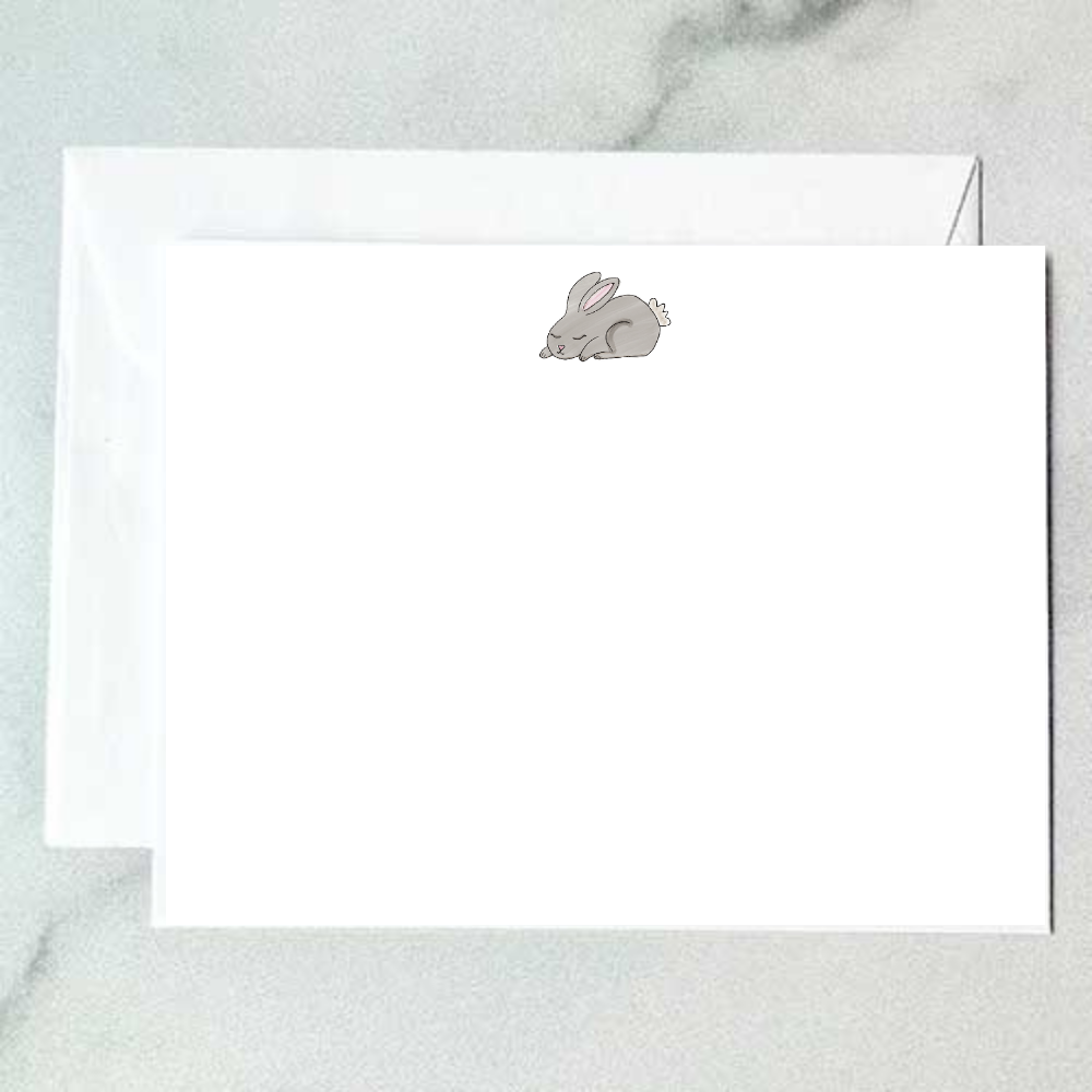 Illustrated gray bunny note card with a sleeping curled rabbit and soft pink ears on a clean white background, designed by Viola and Beatrice Stationers