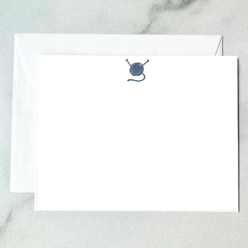 Illustrated yarn ball note card with a blue skein of yarn and two crossed knitting needles on a clean white background, designed by Viola and Beatrice Stationers