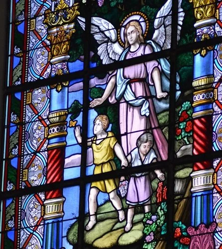 stained glass of an angel walking with two children