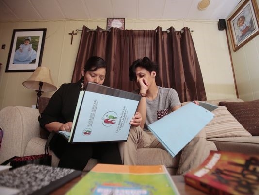 Maria Zuniga, left, and her son Jonathan Lopez, 14, right, look through her Leadership Scholars program binder, Tuesday, April 26, 2016, at her home in Sharonville, Ohio. The program is designed to help the mother of two to navigate the complex field of how to get her children to college. She has two middle-school children who now read, have access to books in the home, and are planning to attending college.(Photo: The Enquirer/Kareem Elgazzar)Buy Photo
