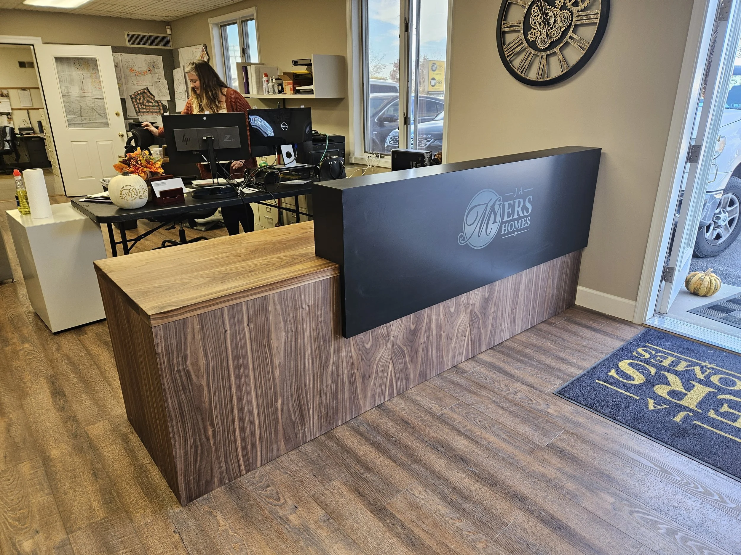 modern office reception desk for home builder, walnut with black counter and vinyl logo