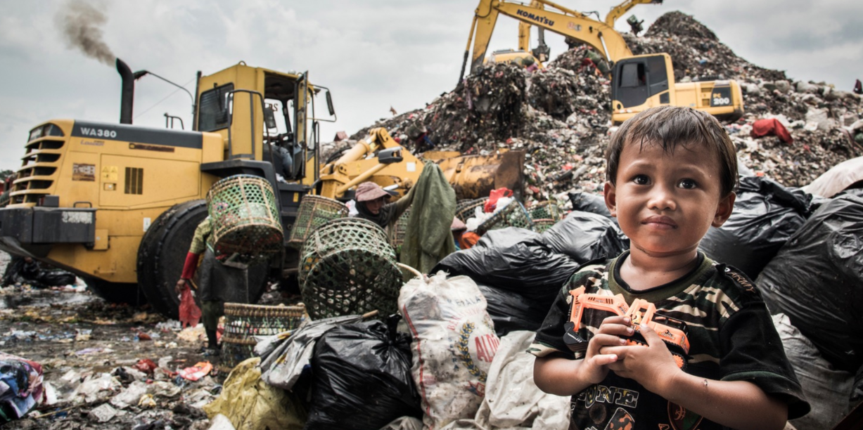 Amir, whose home is amongst these mounds of rubbish, waits for his mum who is working behind him. His favourite toy? A digger. 