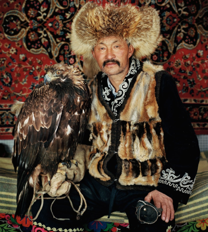 Dalaikhan, a champion hunter, with his 2-year-old eagle. He is wearing fox-skin clothes from previous successful hunts.