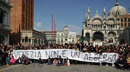 Residents pose with sign reading: Venice is not a hotel. Image Credit: The Telegraph