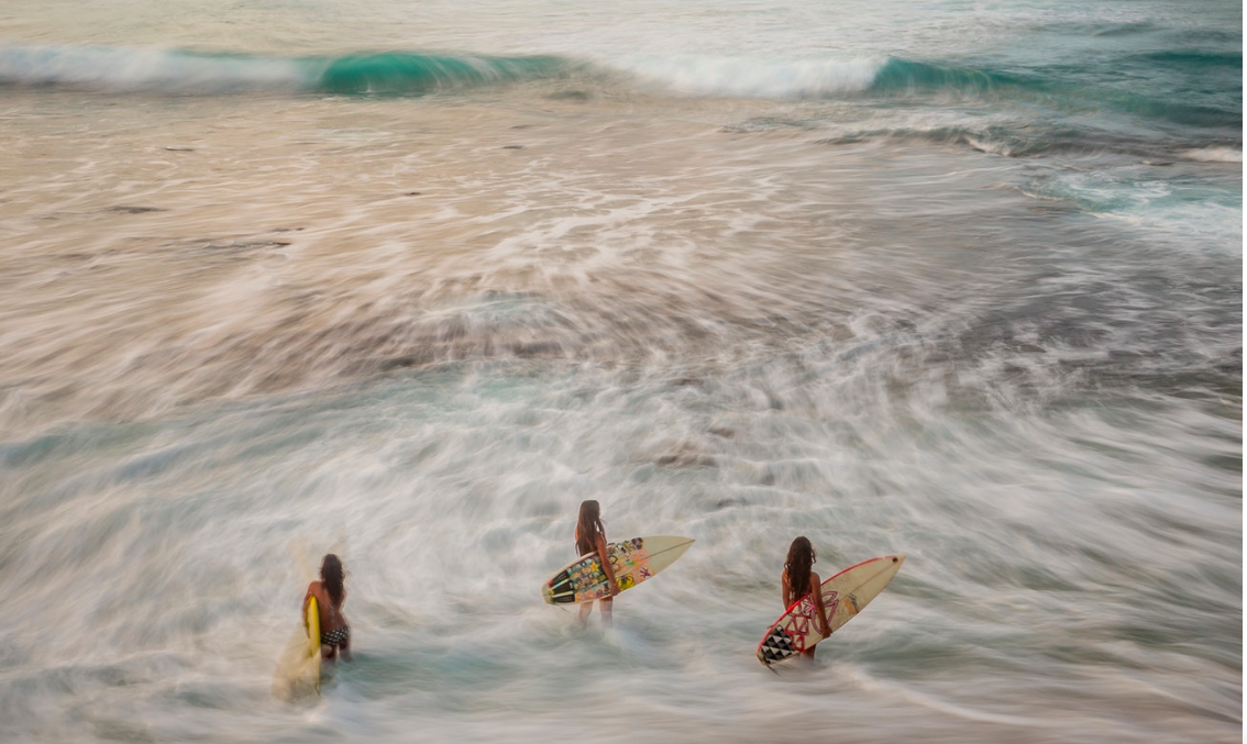 Three Hawaiian sisters wait for the waves in Makaha Beach, Oahu. Hawaii, United States of America