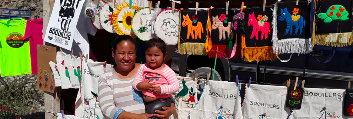 Lucia Orosco holding her daughter, Arely, in Boquillas. Much of the embroidery created here reads ‘no el muro’ (no wall). Matthew Moran, CC BY-ND
