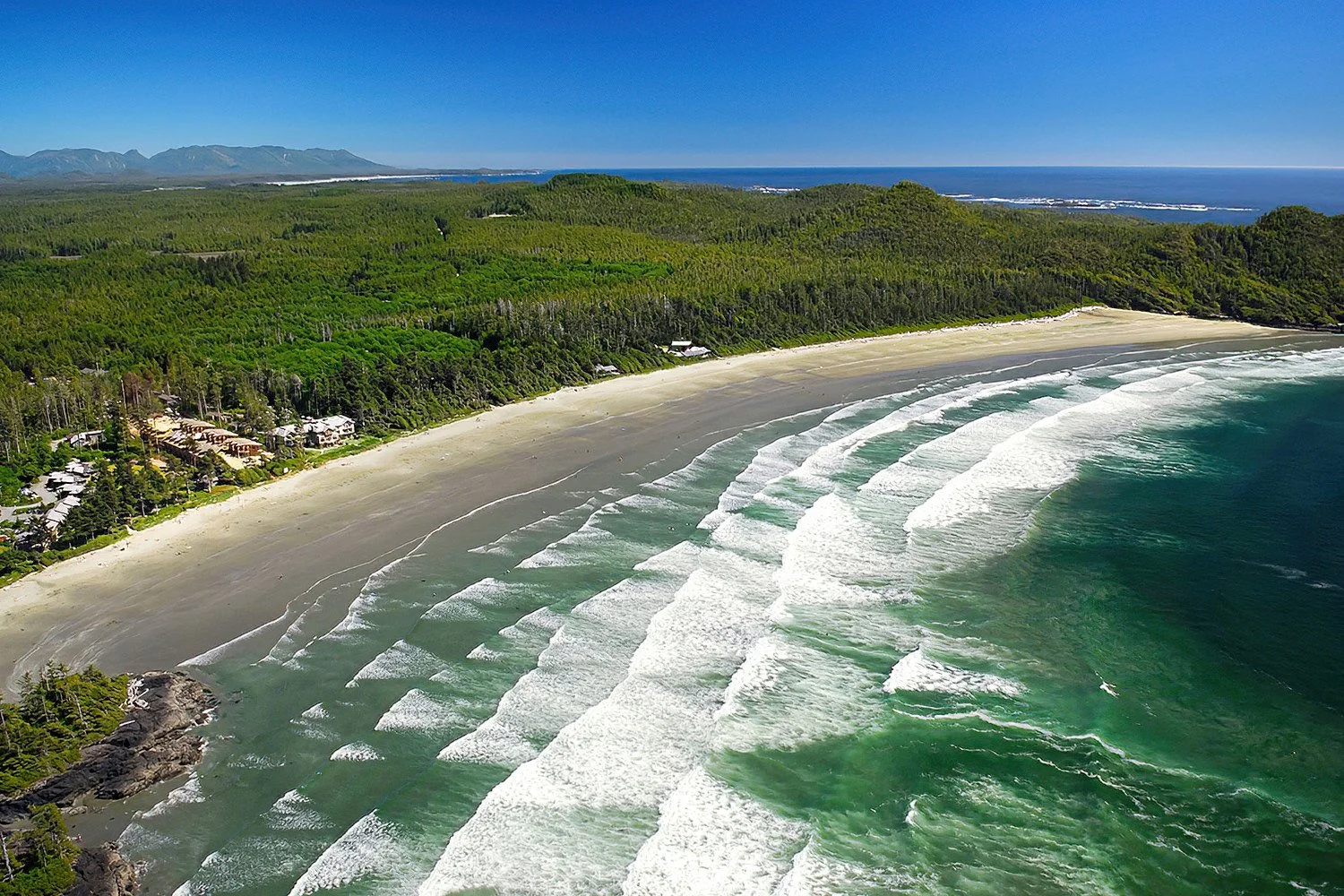 An aerial photo of Cox Bay, Vancouver Island, BC, Canada.  It is a world-renowned surf beach famous for its powerful waves, stunning sunsets, and vibrant surfing community.