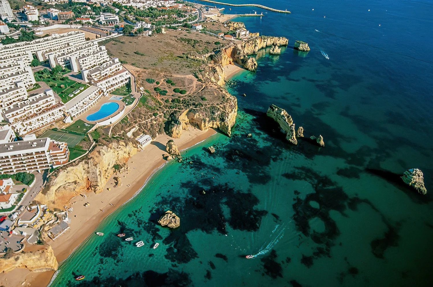 An aerial photo of the Algarve region Portugal.  The beaches of the Algarve are famed for their golden cliffs, turquoise waters, and hidden coves that feel both dramatic and serene.