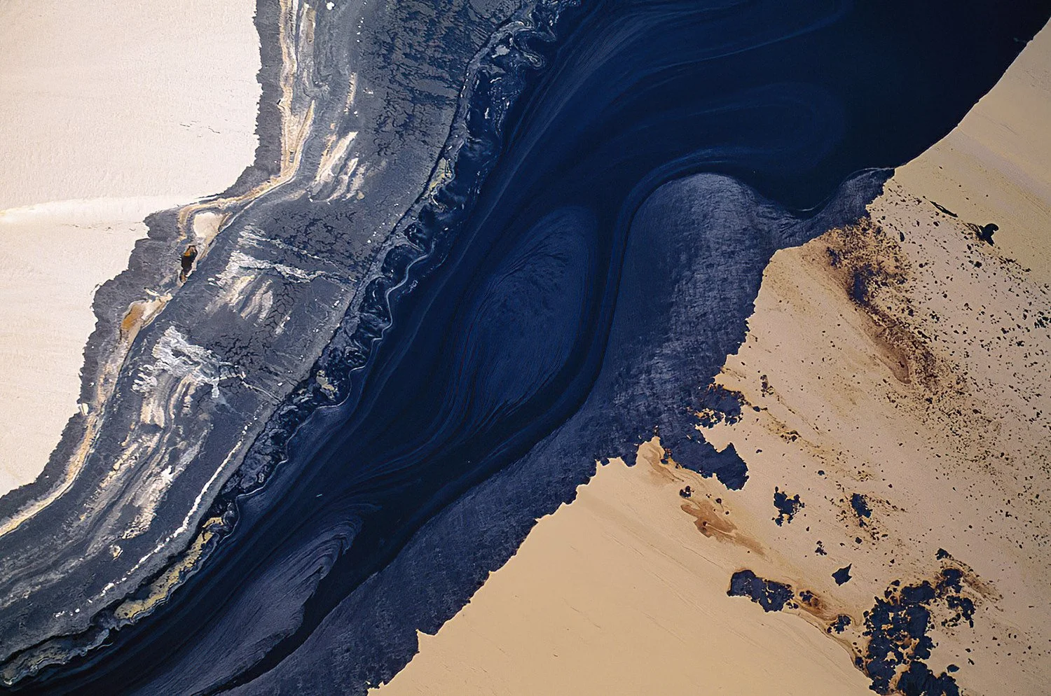 An aerial photo of the Alberta Tar Sands, Alberta, Canada.  Vast tailings ponds form huge pools of black, oily-looking liquid composed of water, residual bitumen, and fine sediments.