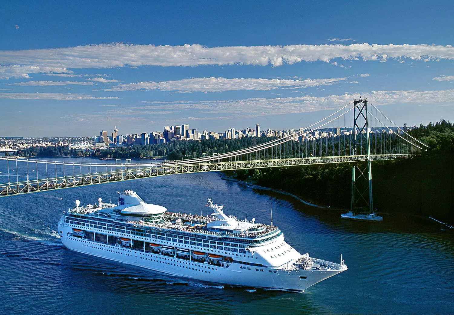 An aerial photo of Legend of the Seas passing under the Lions Gate Bridge as it departs Vancouver, BC, Canada