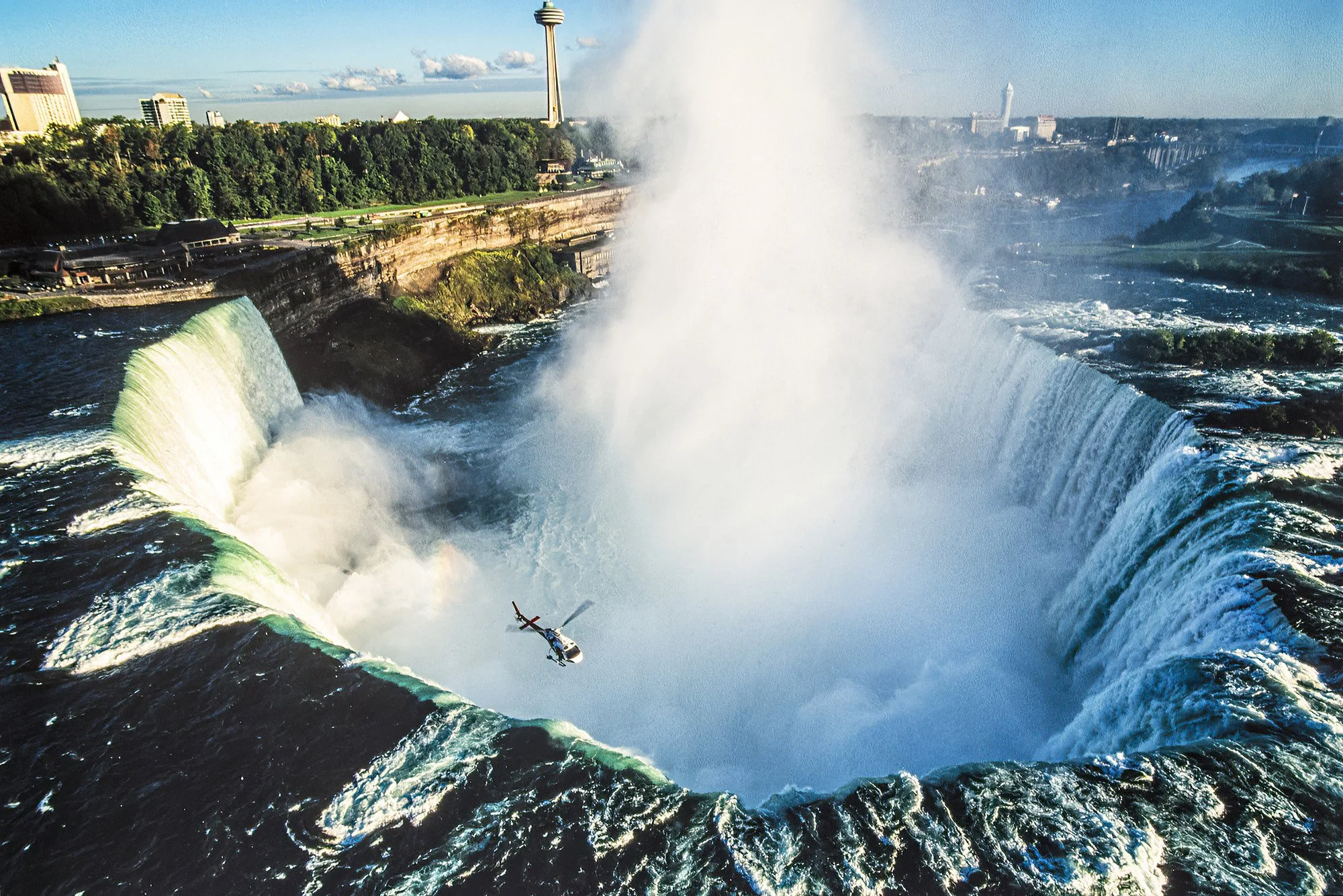 An aerial photo of a helicopter shoot over Niagara Falls.  A world-famous set of massive waterfalls on the Niagara River, renowned for their powerful flow and breathtaking beauty.