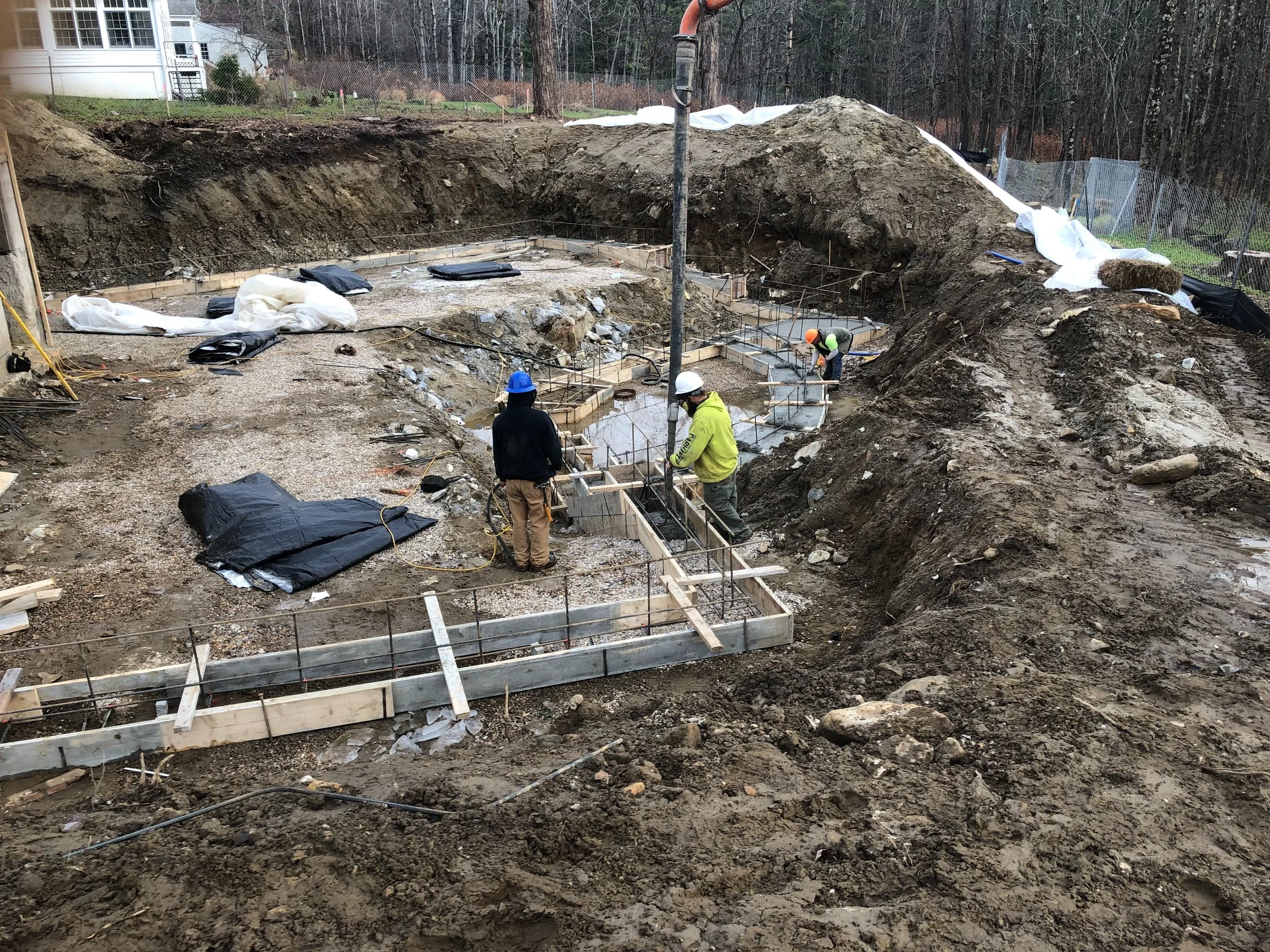 WORKERS DIRECTING THE DISCHARGED CONCRETE INTO THE FOOTING FORMS