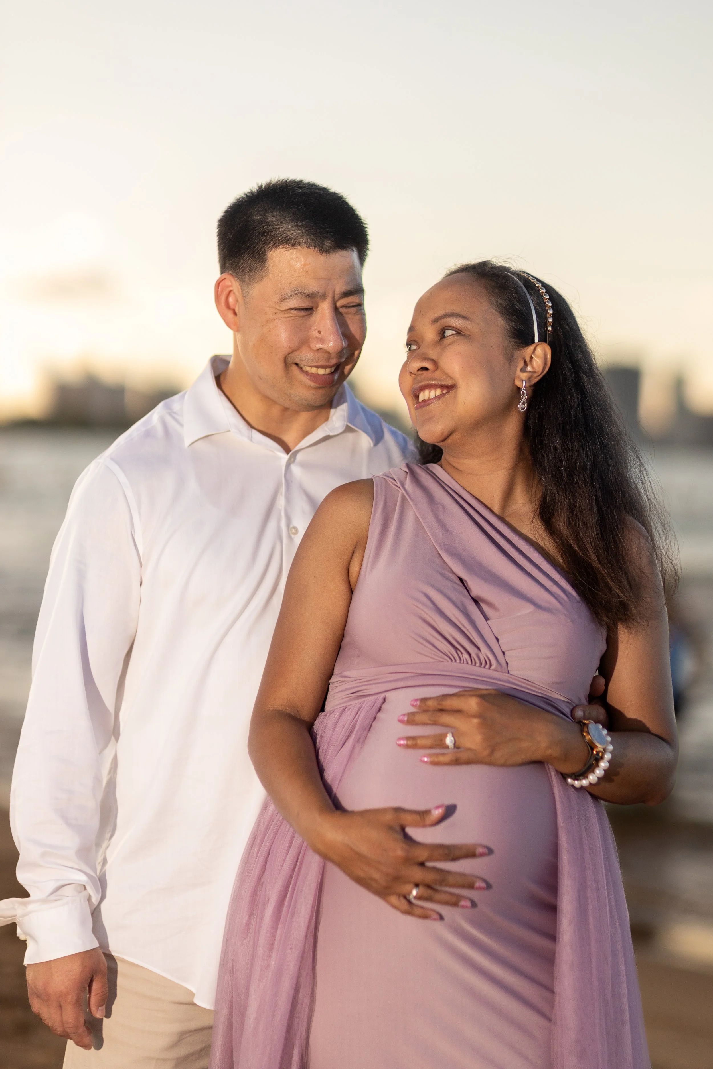 Pregnant Couple Looking lovingly into each others eyes on the beach