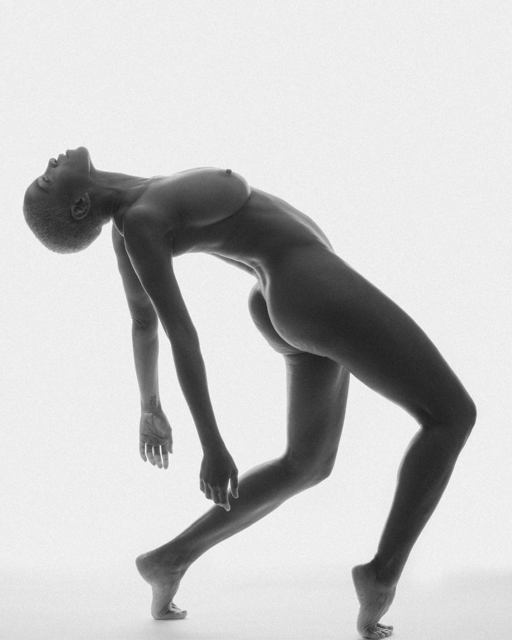 A black and white photograph of a woman performing a handstand.