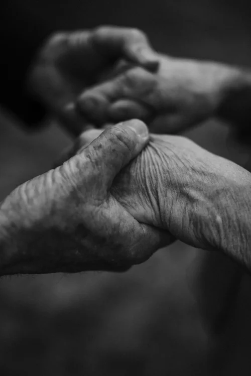old couple holding hands close up in black and white