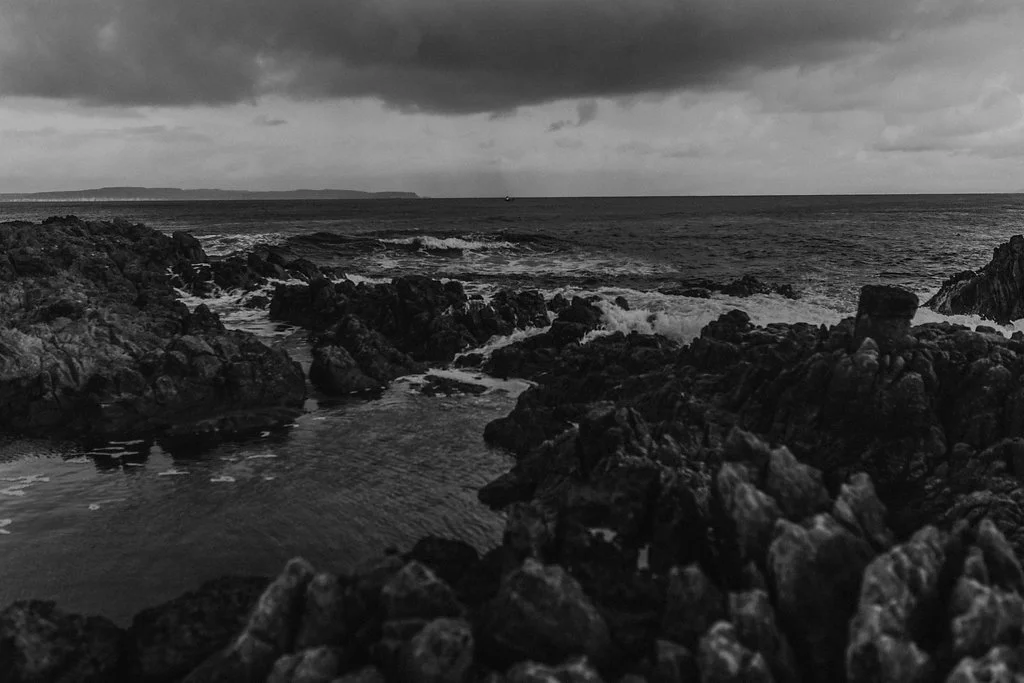 dark clouds and waves roll in over jagged rocks at rathlin island coast by ballycastle in northern ireland by meri daugherty photography